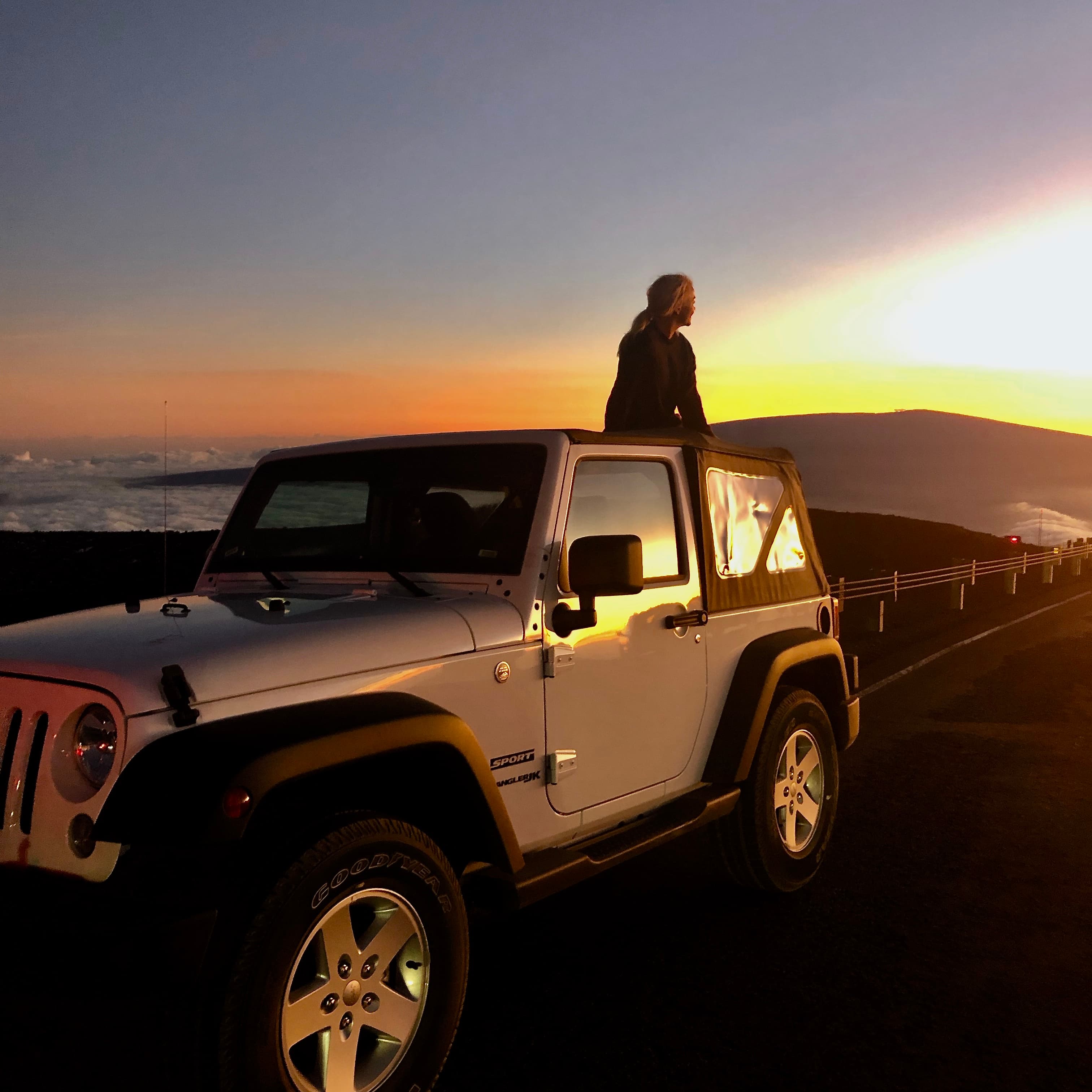 Advisor sitting on the back of a jeep at sunset