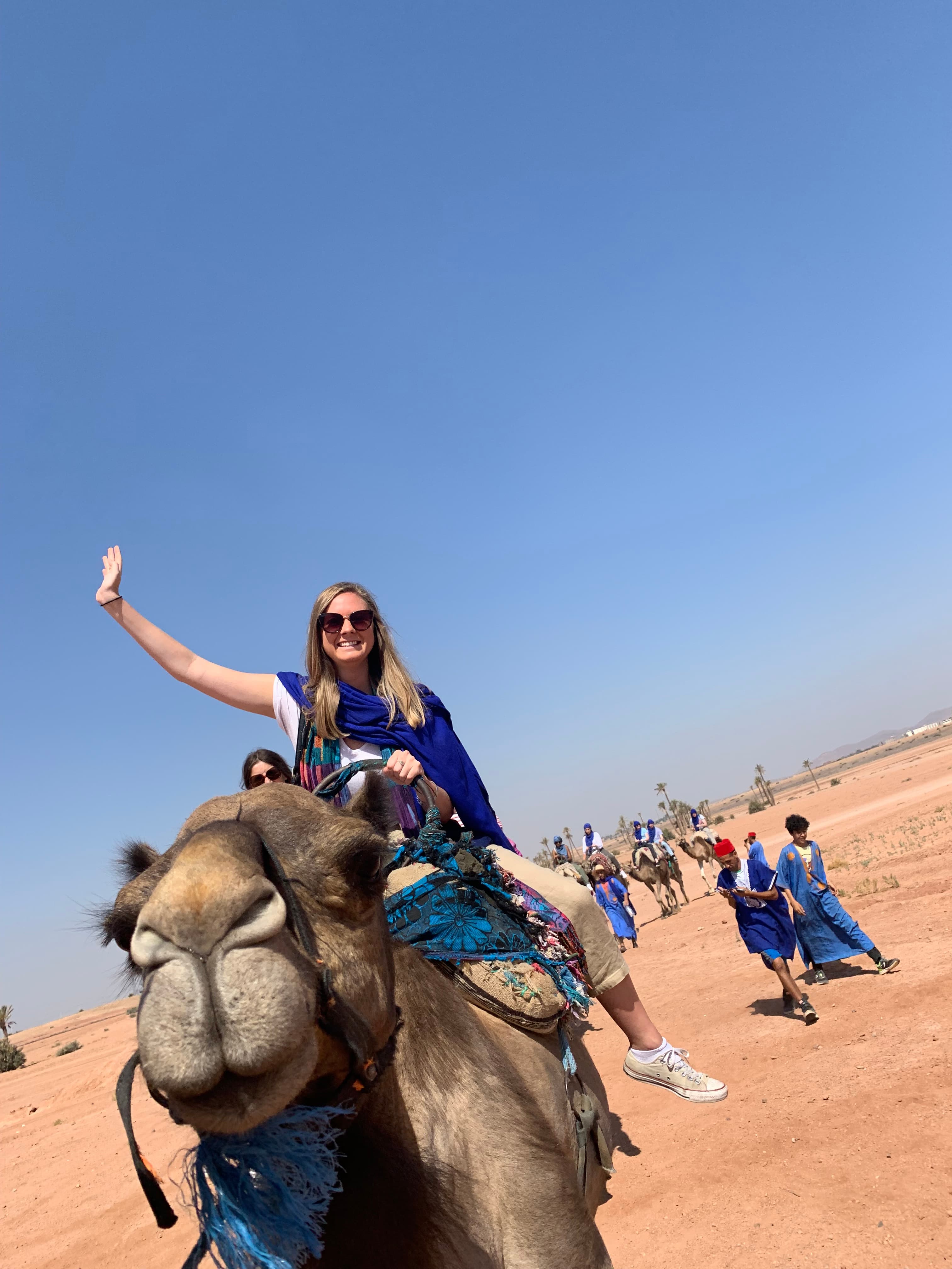 Advisor on camelback riding through the desert under clear skies