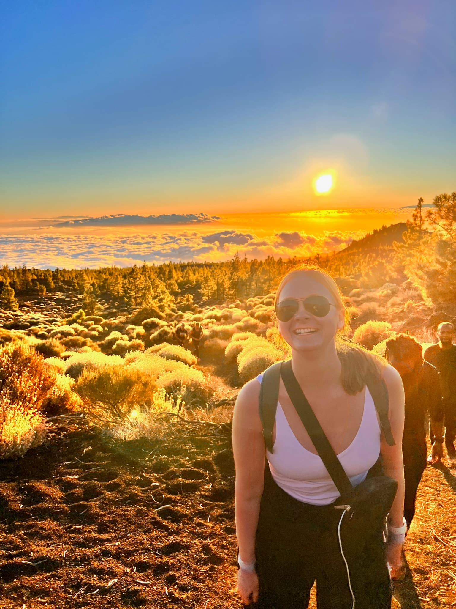 Advisor smiling on a sunset hike with her surroundings bathed in golden light