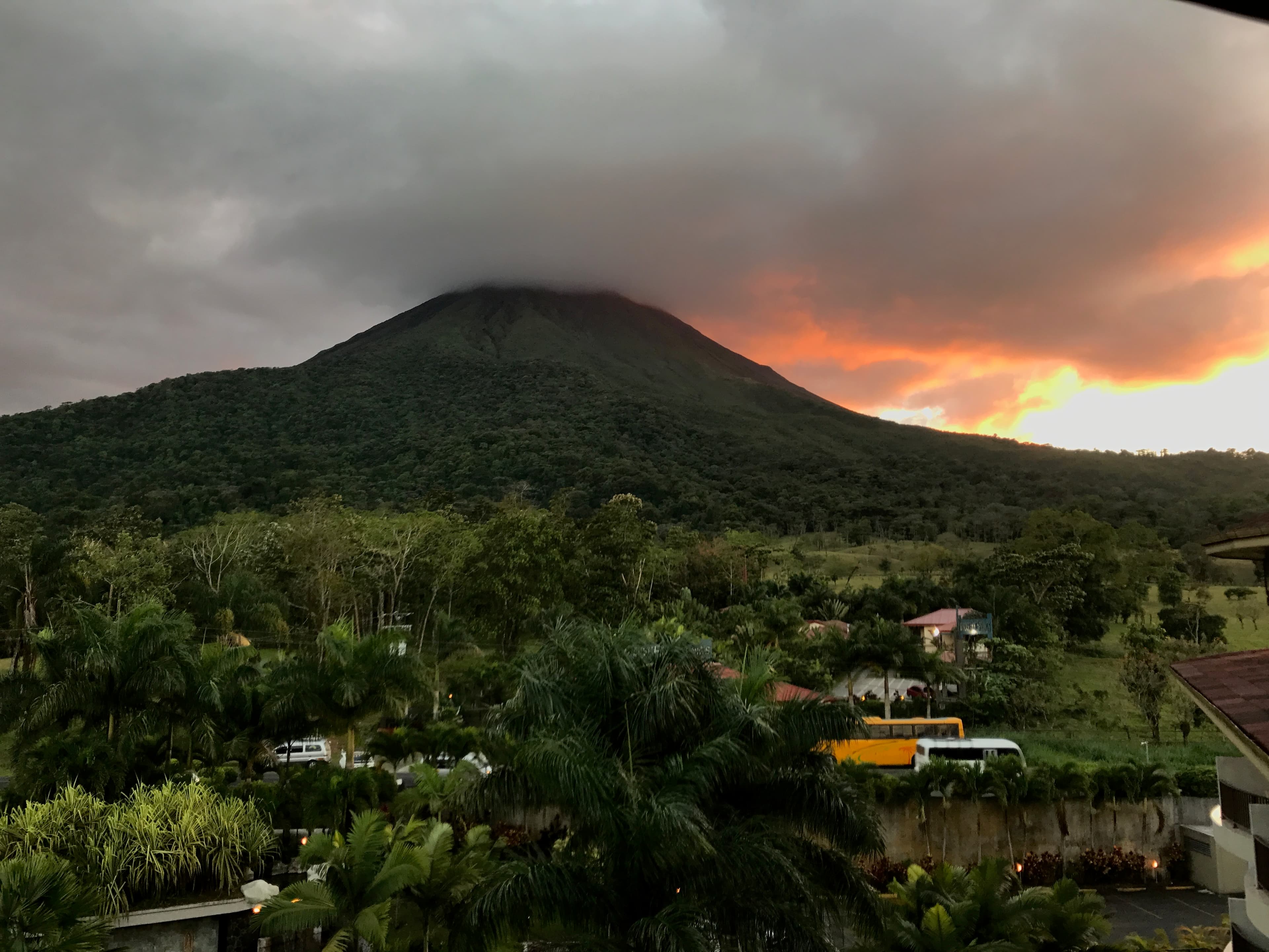 View of a lush mountain rising into the clouds at sunset