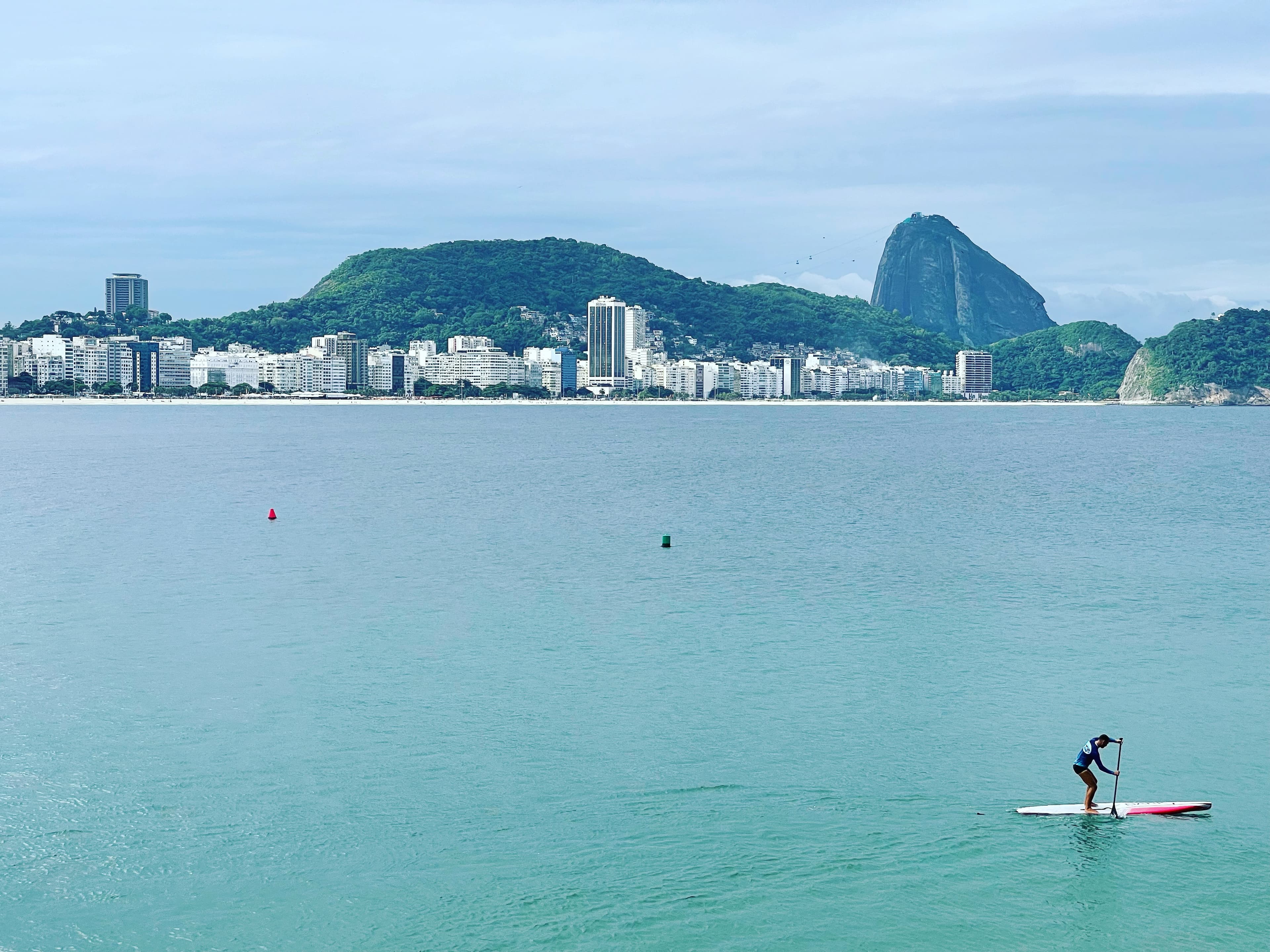 View of a person paddle boarding against a coastal cityscape