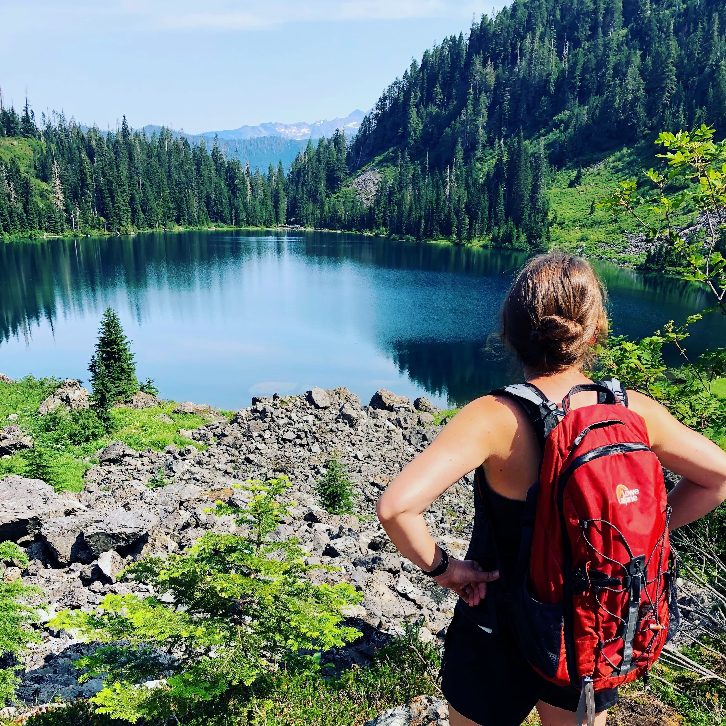 View of advisor facing a glassy lake and carrying a red backpack