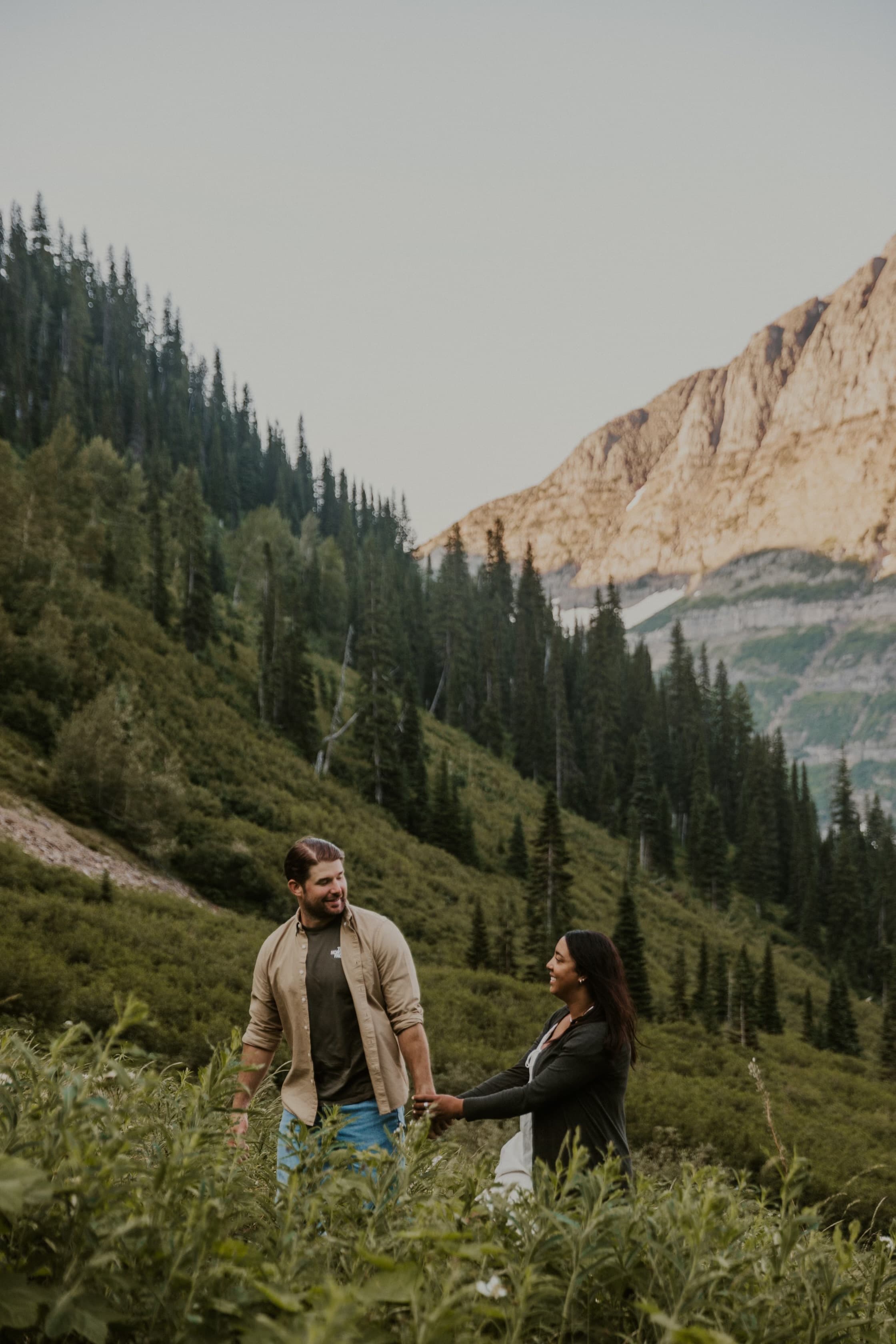 View of a couple holding hands and walking through a scenic mountain landscape