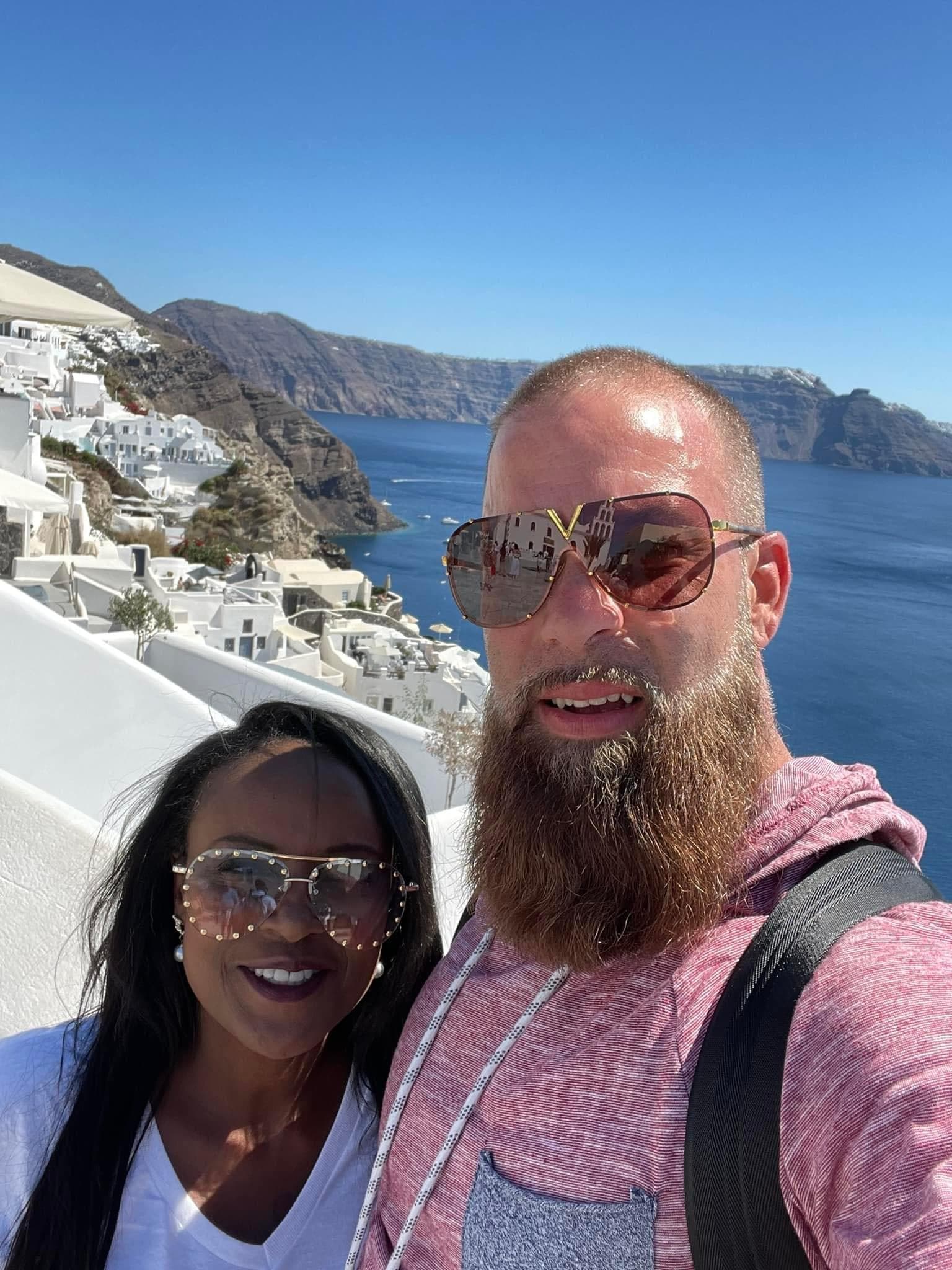 Advisor and partner taking a selfie outdoors with a sea view behind them