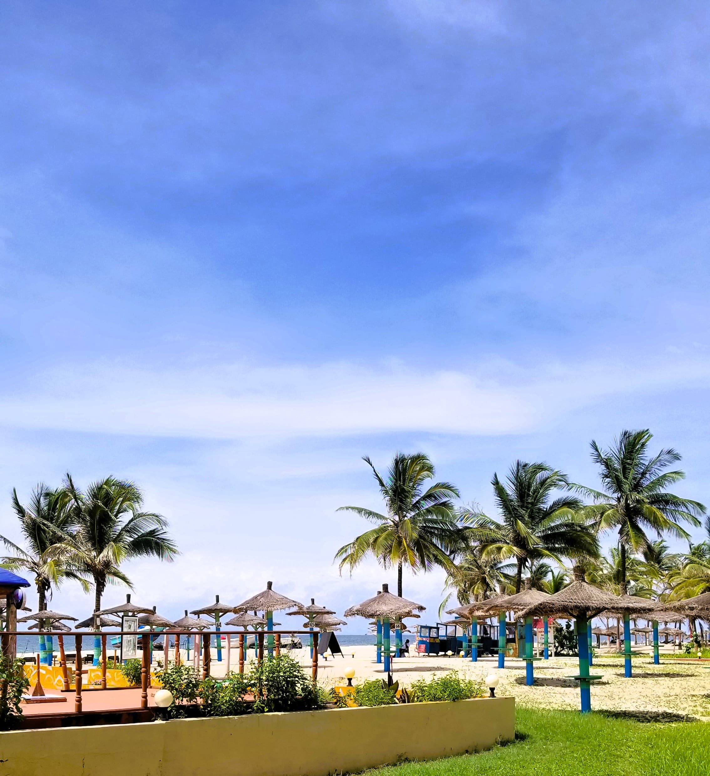 View of thatched umbrellas on a resort beach under sunny skies