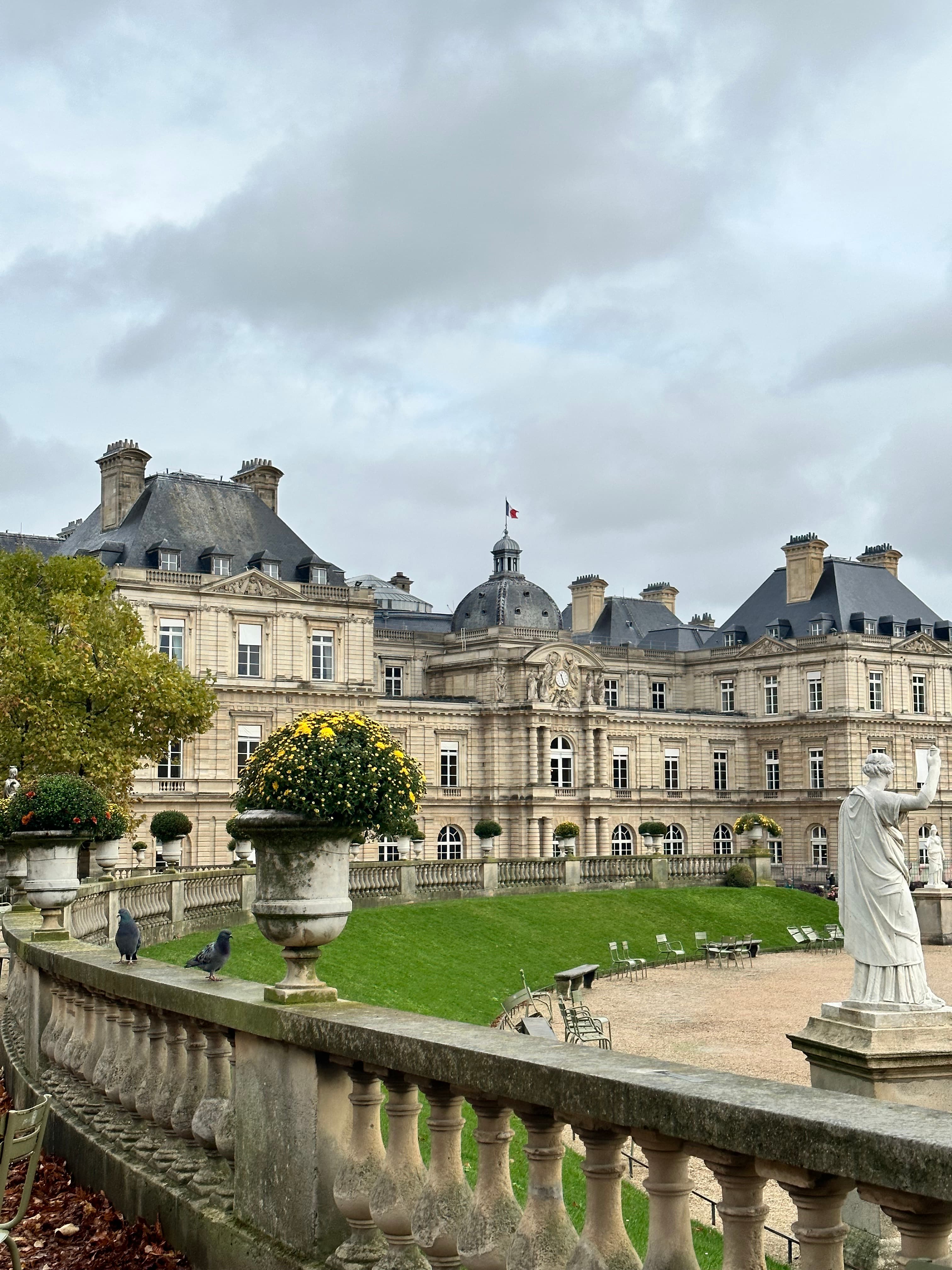 View of a green lawn with white statues in front of a grand building