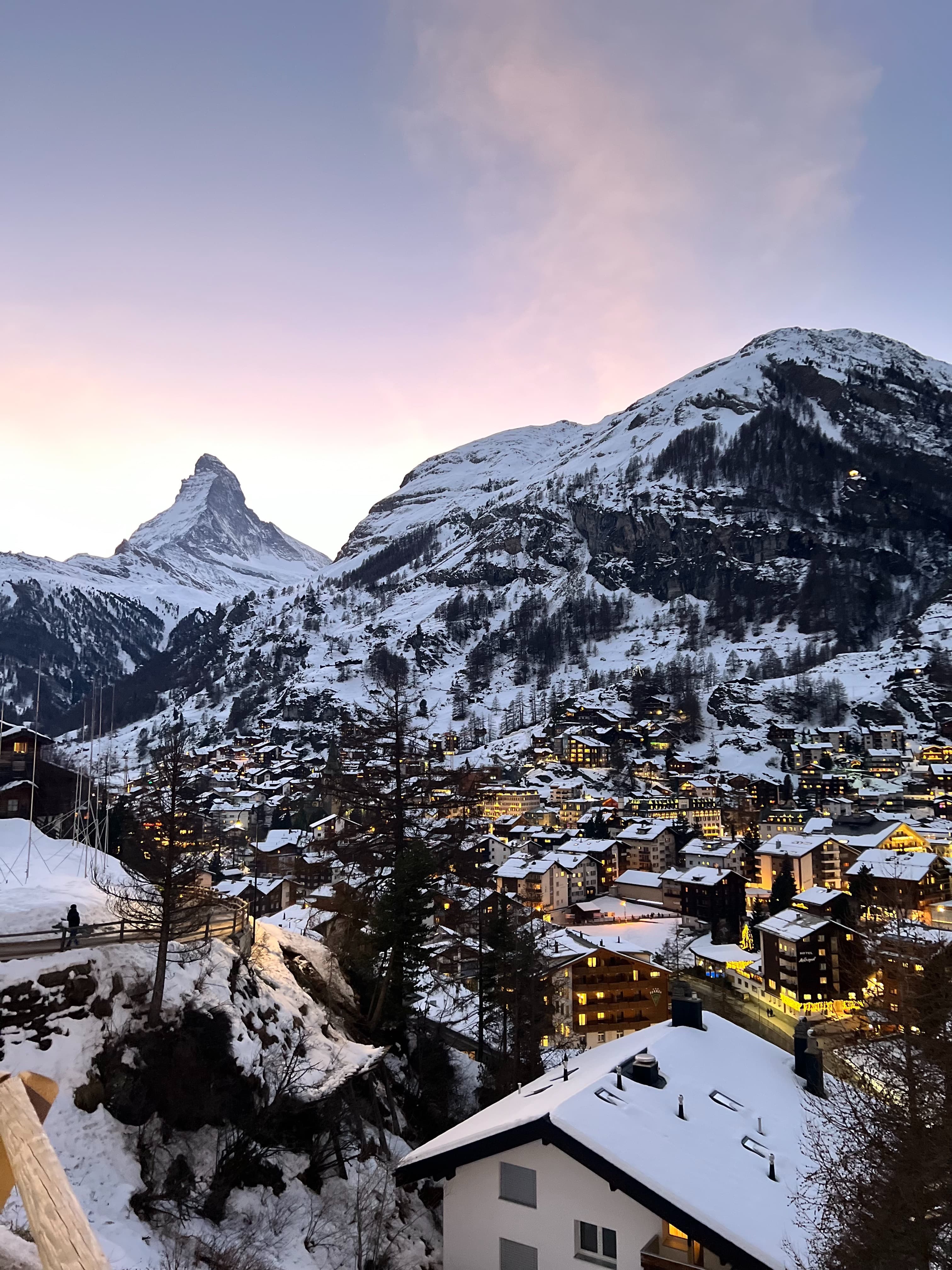 View of snow-capped mountains and buildings lit up in the evening.