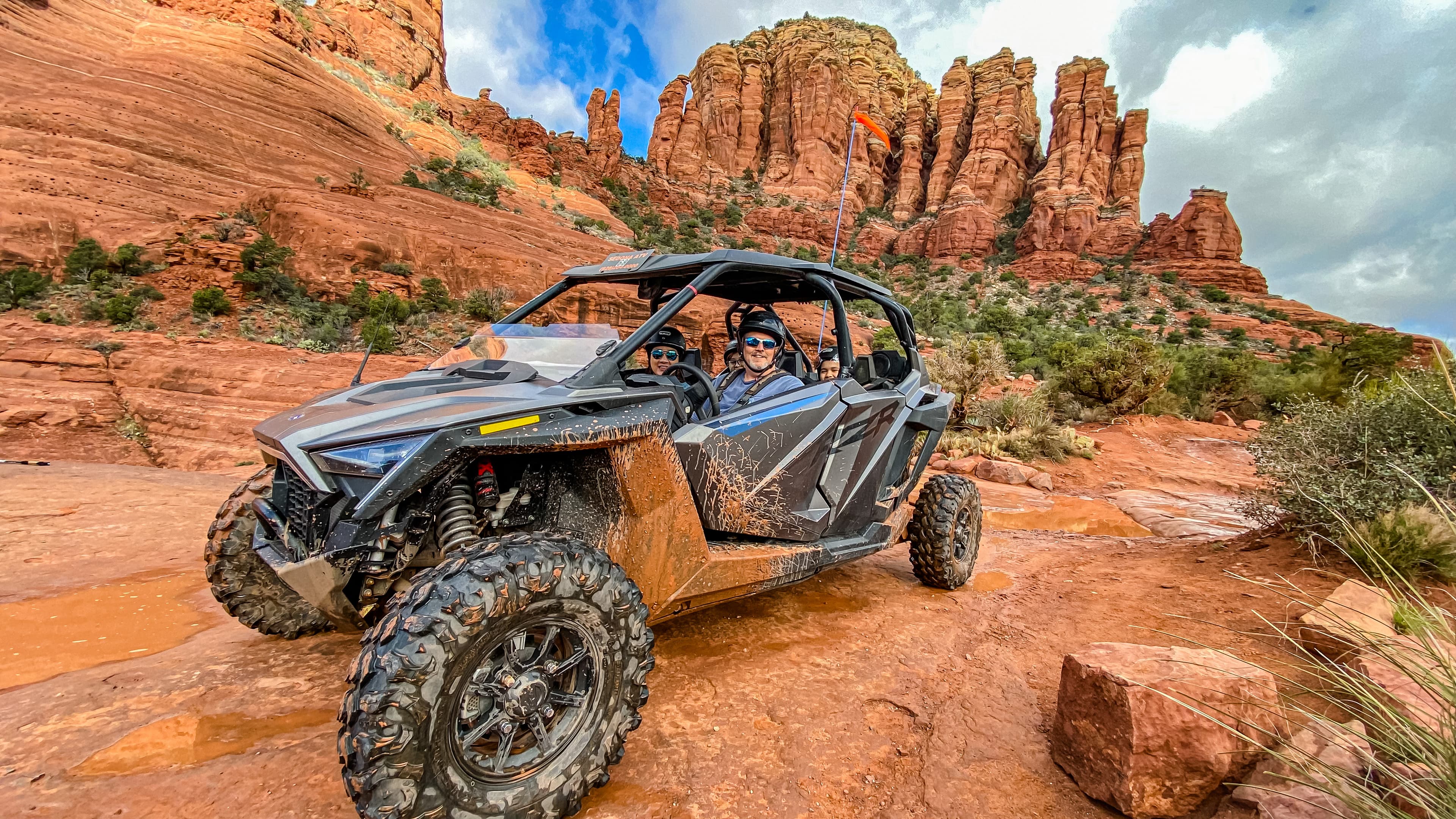 View of a dirty 4-wheel vehicle driving through a red desert area