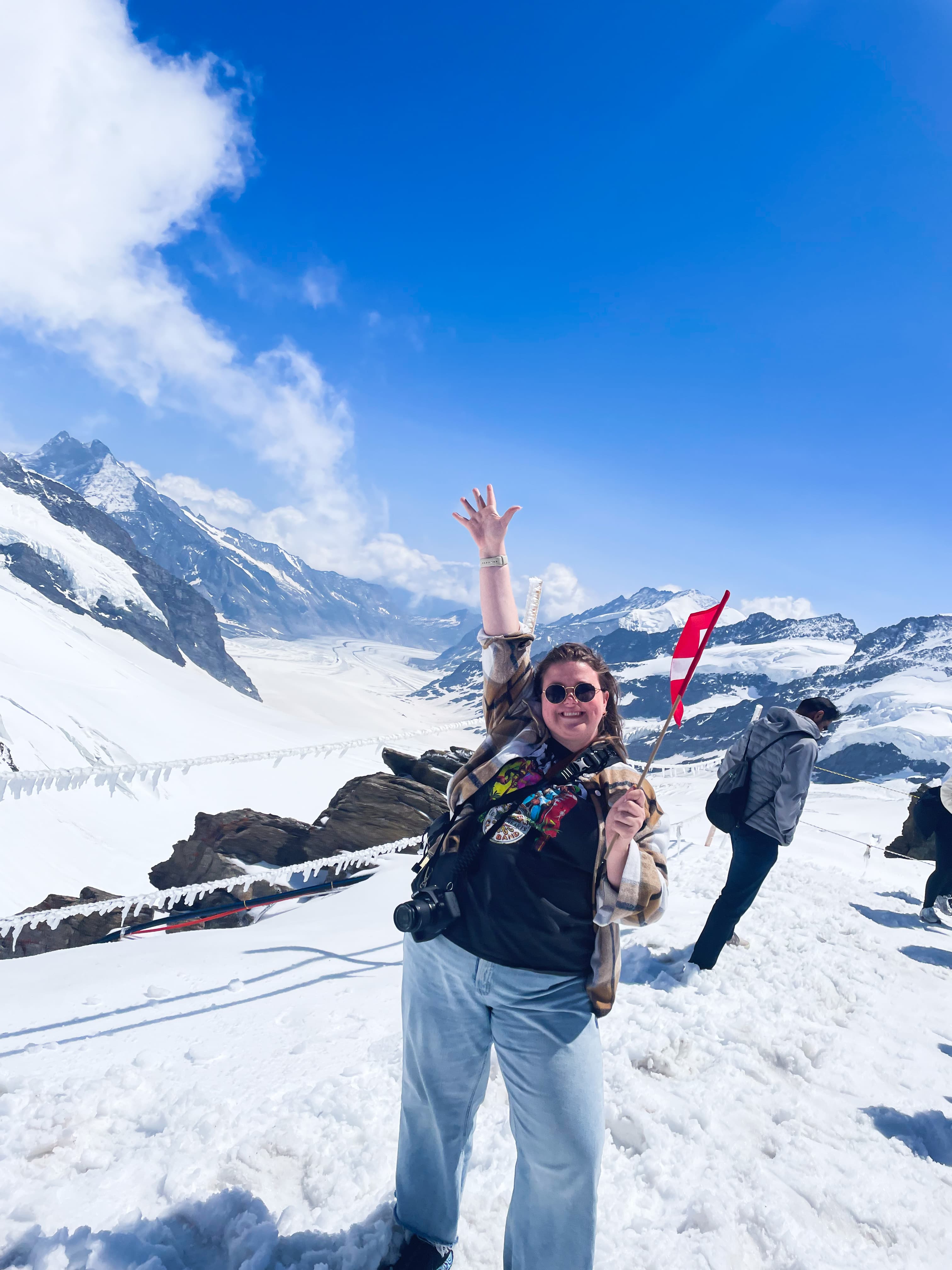 Advisor posing with an arm raised on a snowy mountain under sunny skies