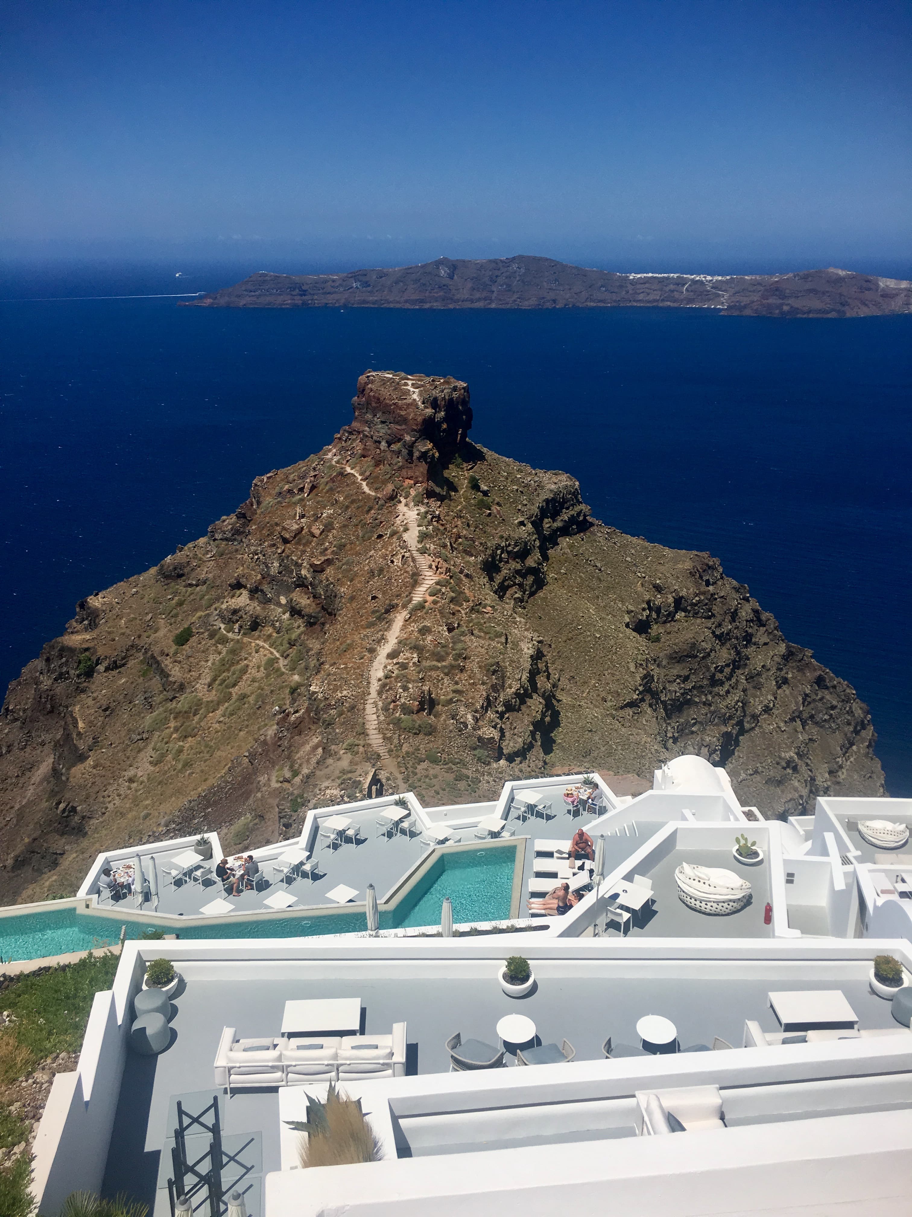 Rooftop view of a home with a pool overlooking the ocean on a sunny day.