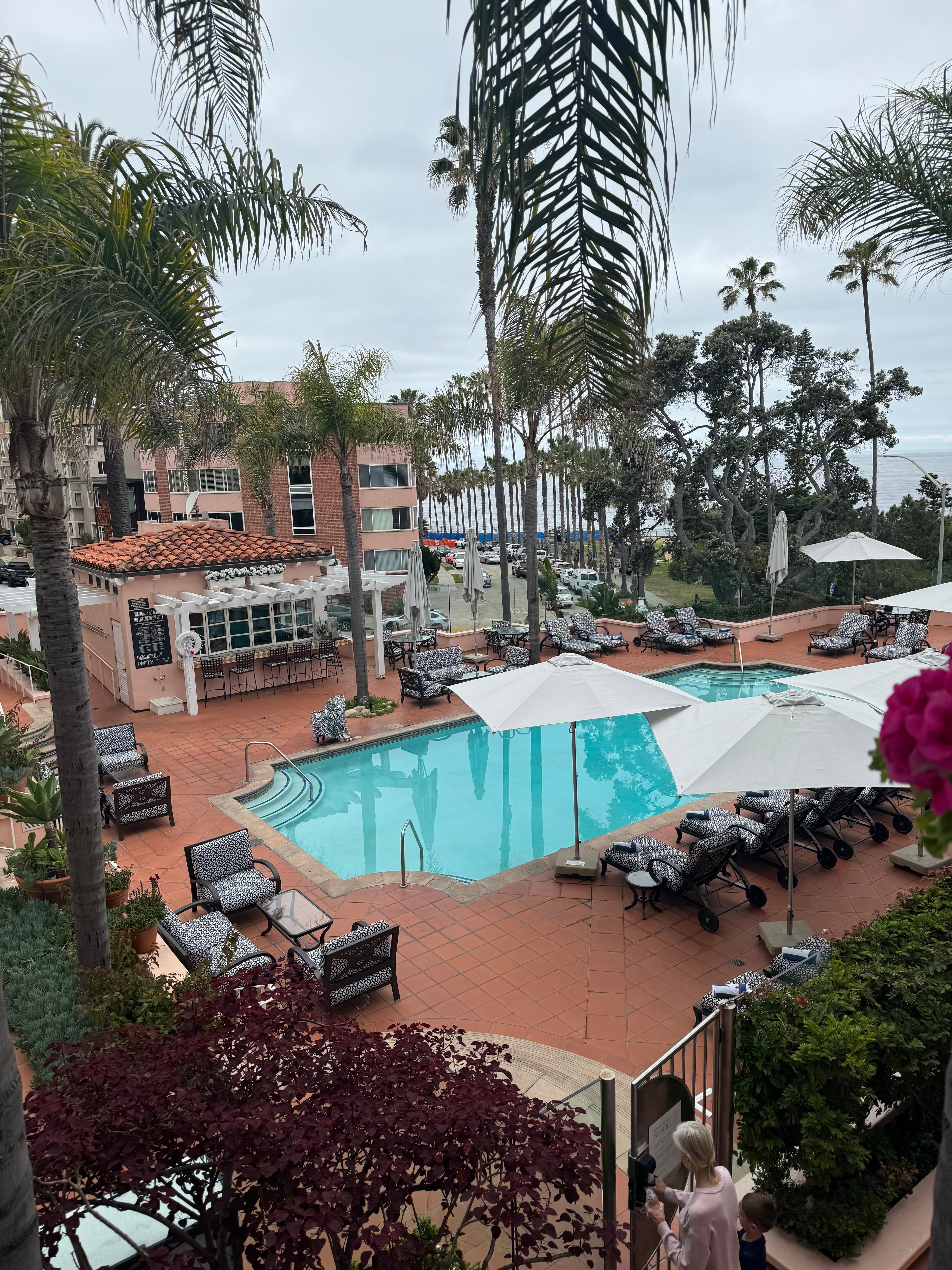 A pool at a resort surrounded by palm trees during the daytime.