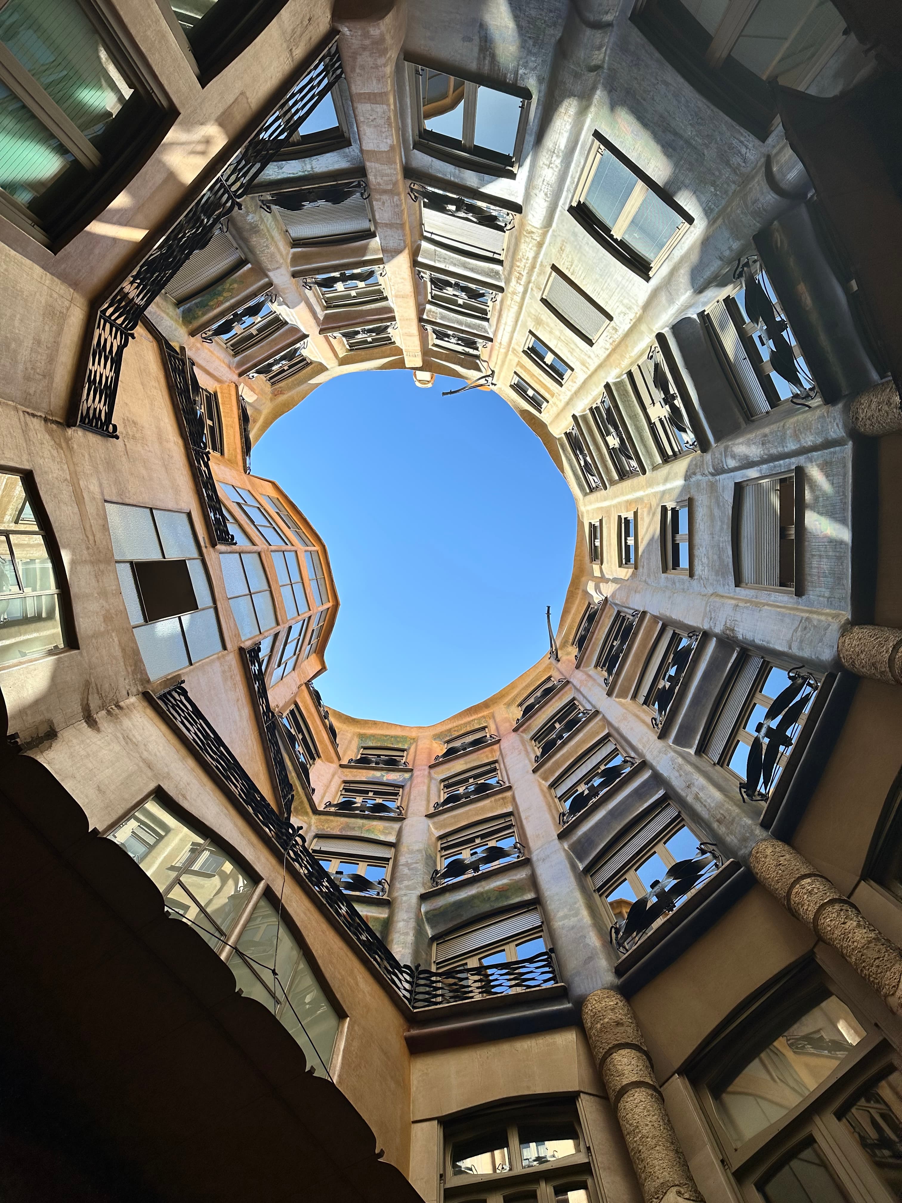 Upwards facing view of a circular shaped building, a circle of blue sky visible at the top