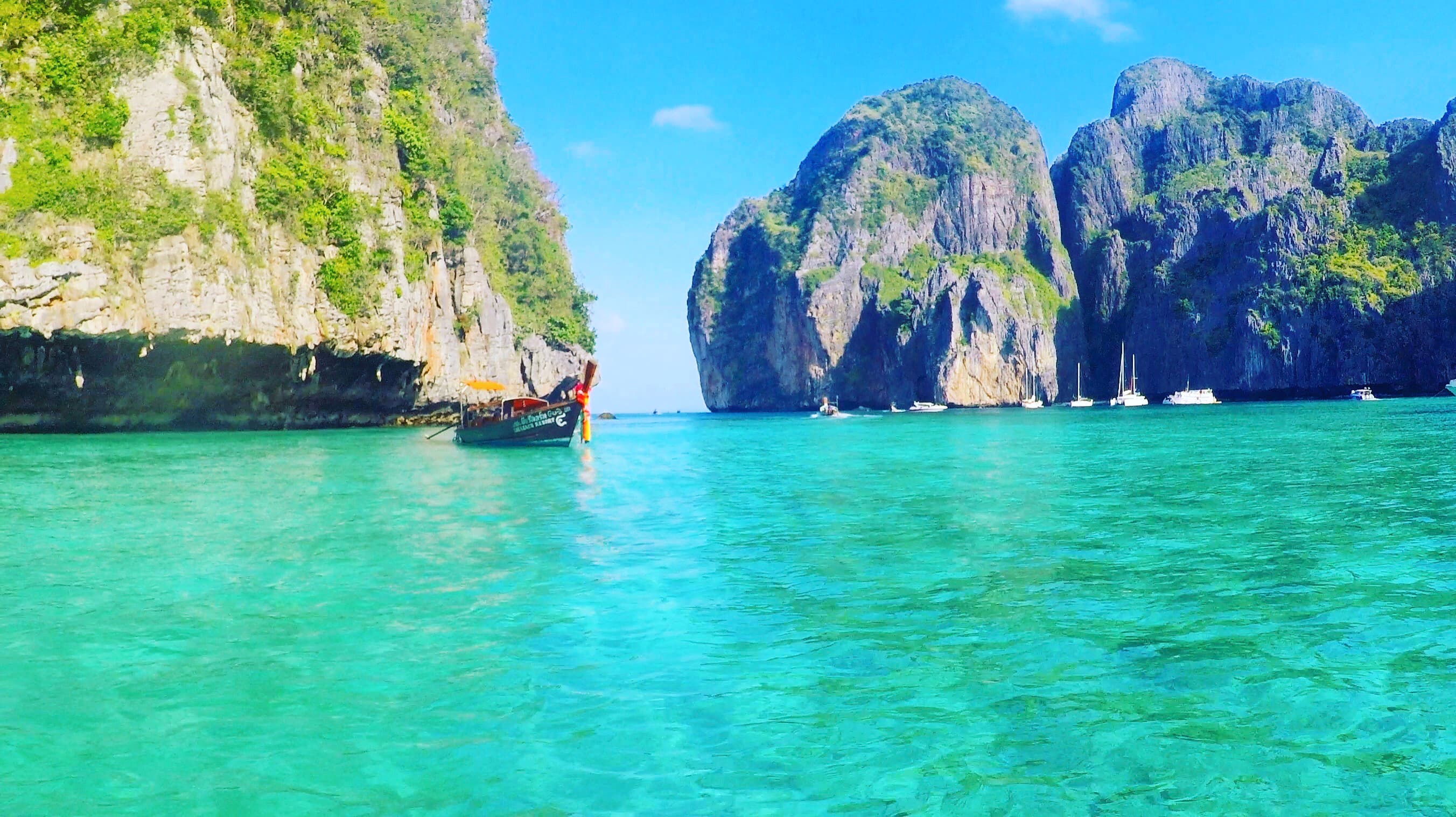 View of a bright turquoise sea and nearby rock formations on a sunny day