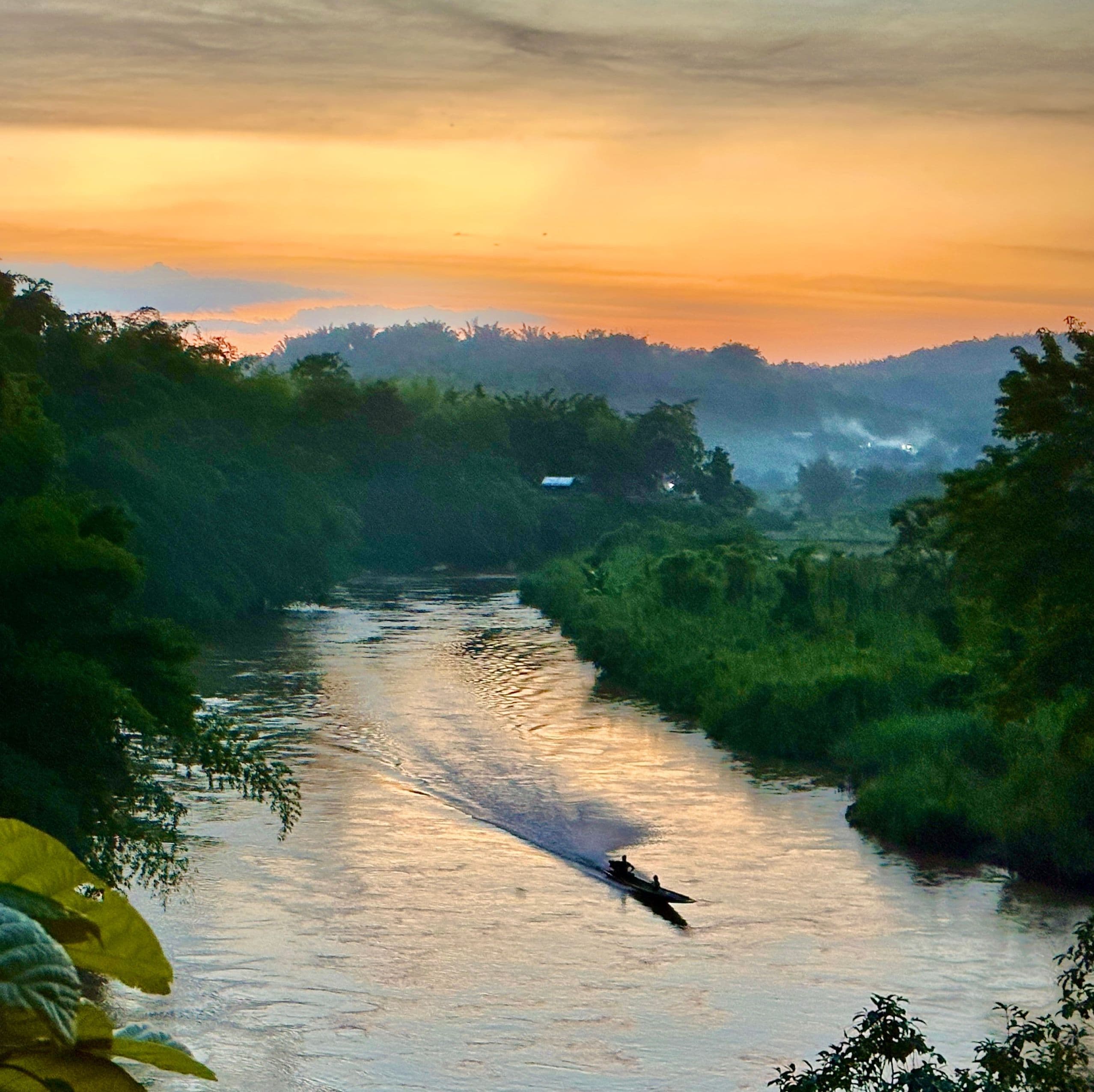 A vie of a water way with foliage in the distance at sunset.
