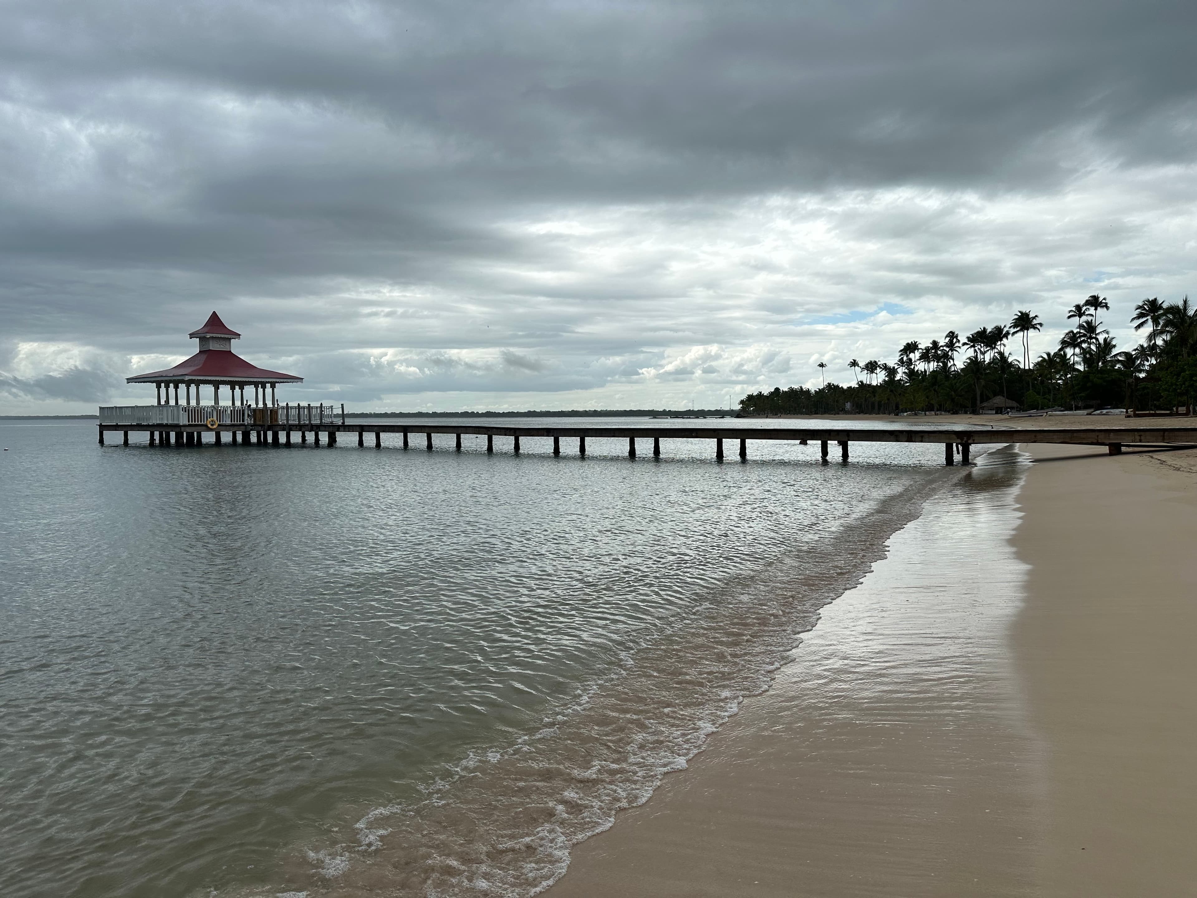 A pier at the beach during overcast weather.