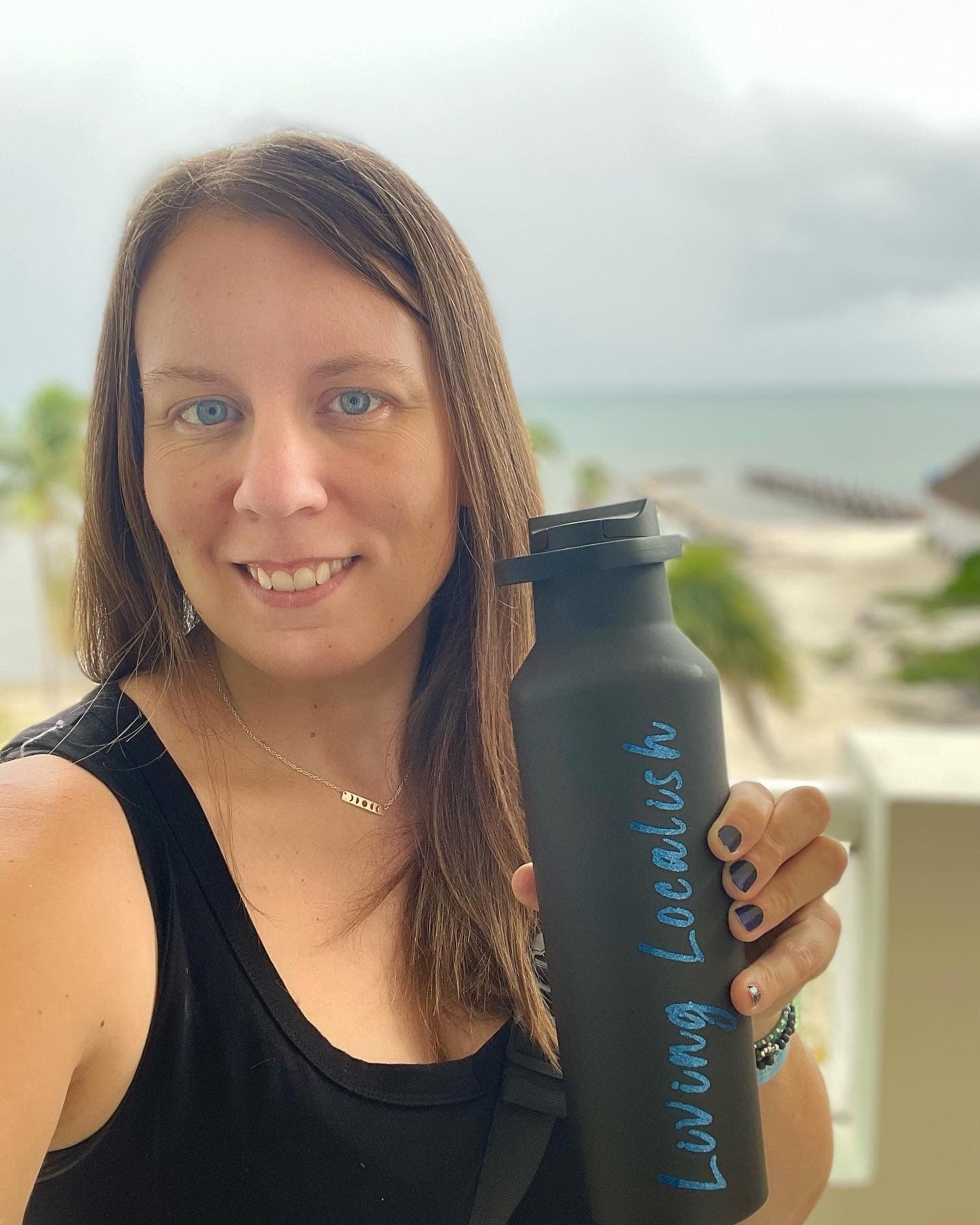 An advisor wearing a black tank top and holding a black water bottle while posing for a selfie.