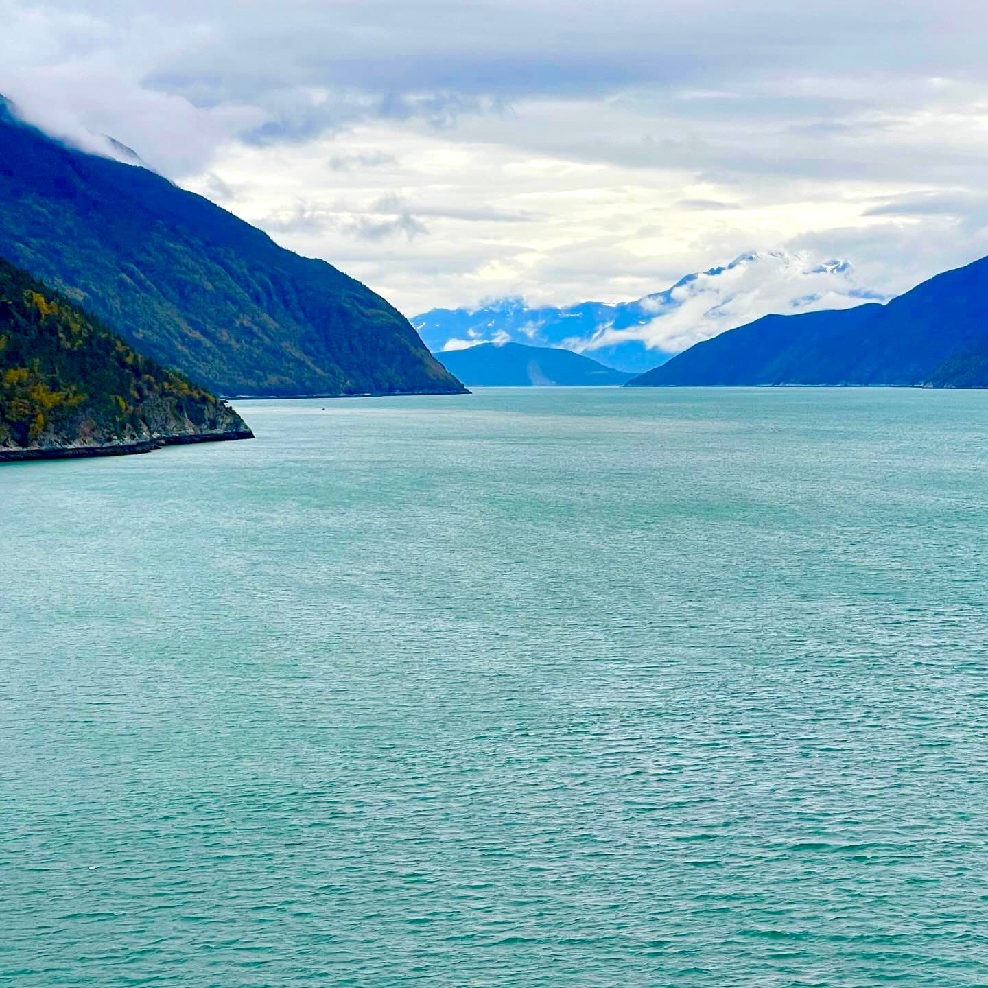 A view of a lake and mountains beneath a cloudy sky.