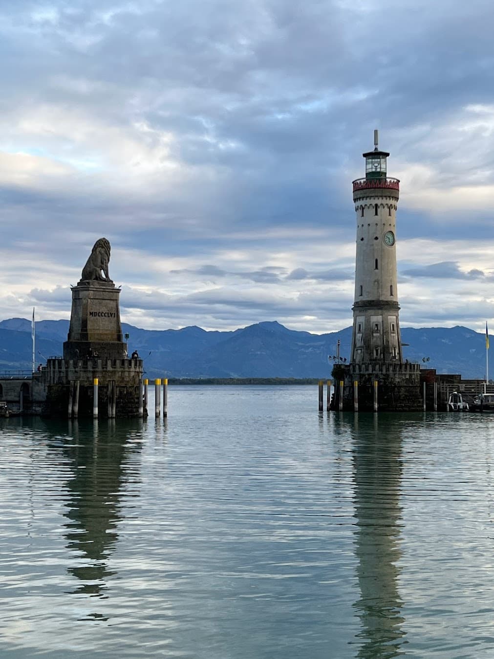 A view of a lighthouse and lake with mountains in the background.