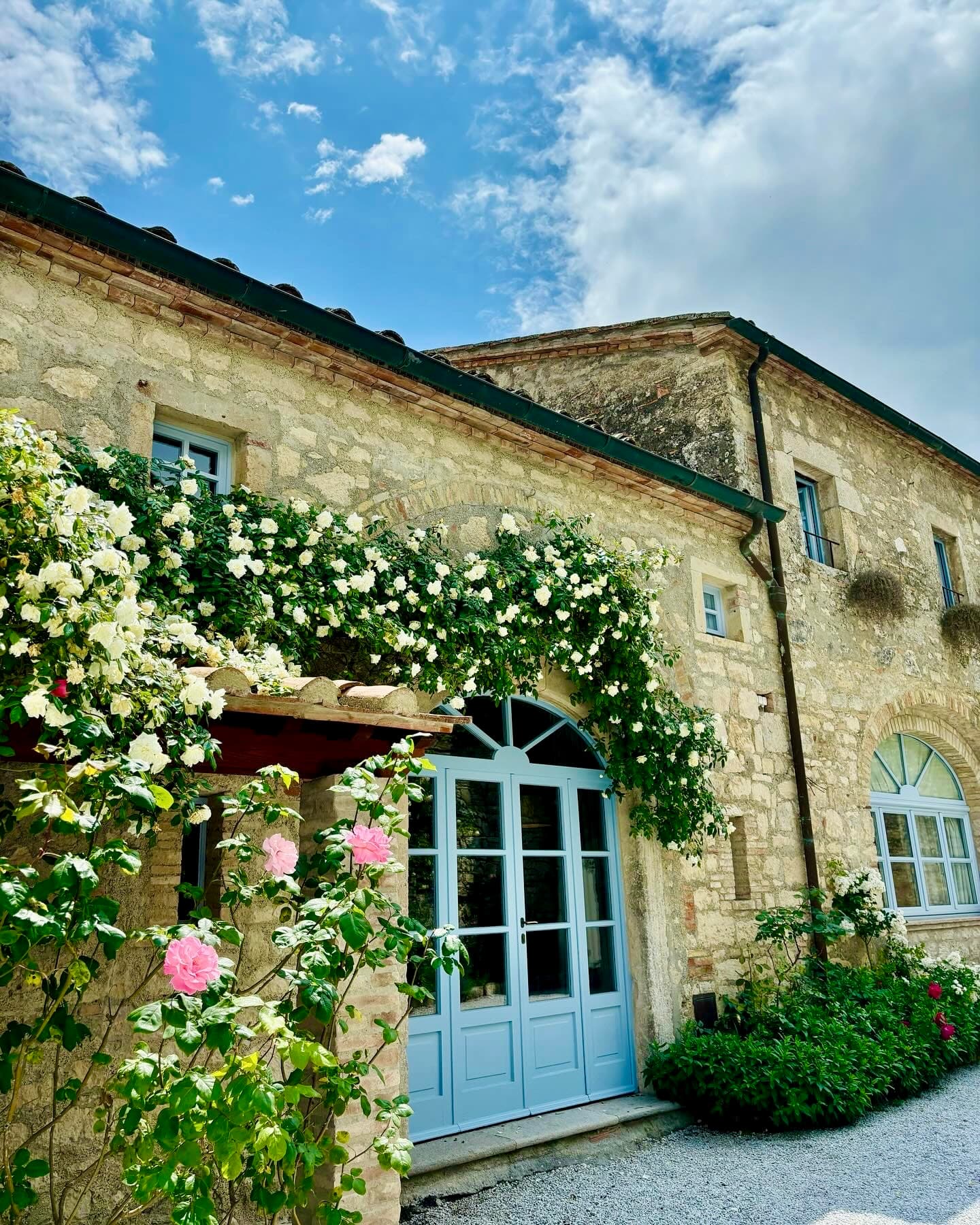 Exterior of a stone cottage with flowering vines growing on the walls.