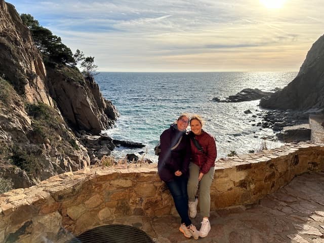 Monica and friend posing in front of some mountains and the ocean.