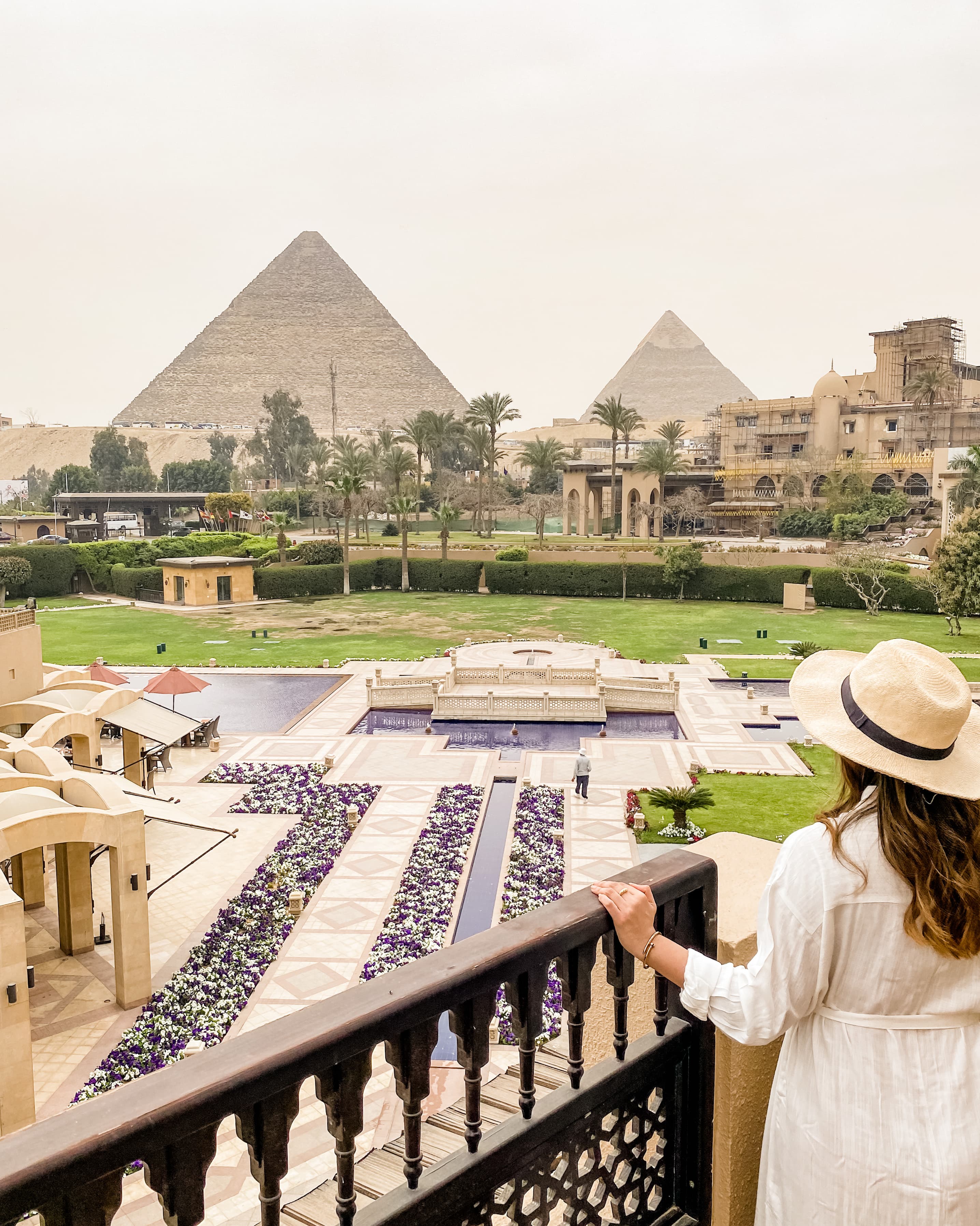 Advisor on a luxury hotel balcony looking out at fountains and pyramids.