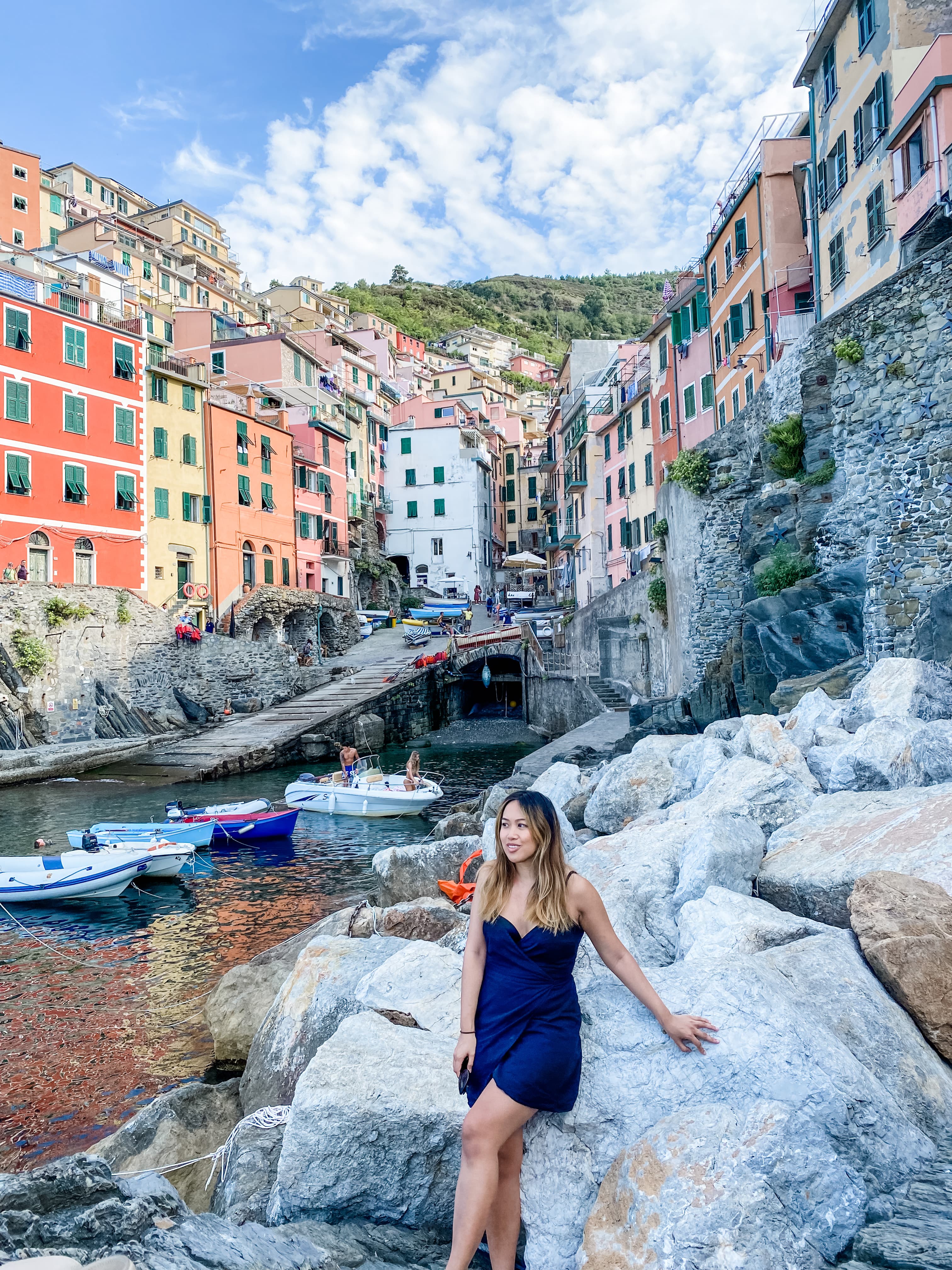 Advisor sitting on a rock next to a harbor with colorful homes on the hills above.