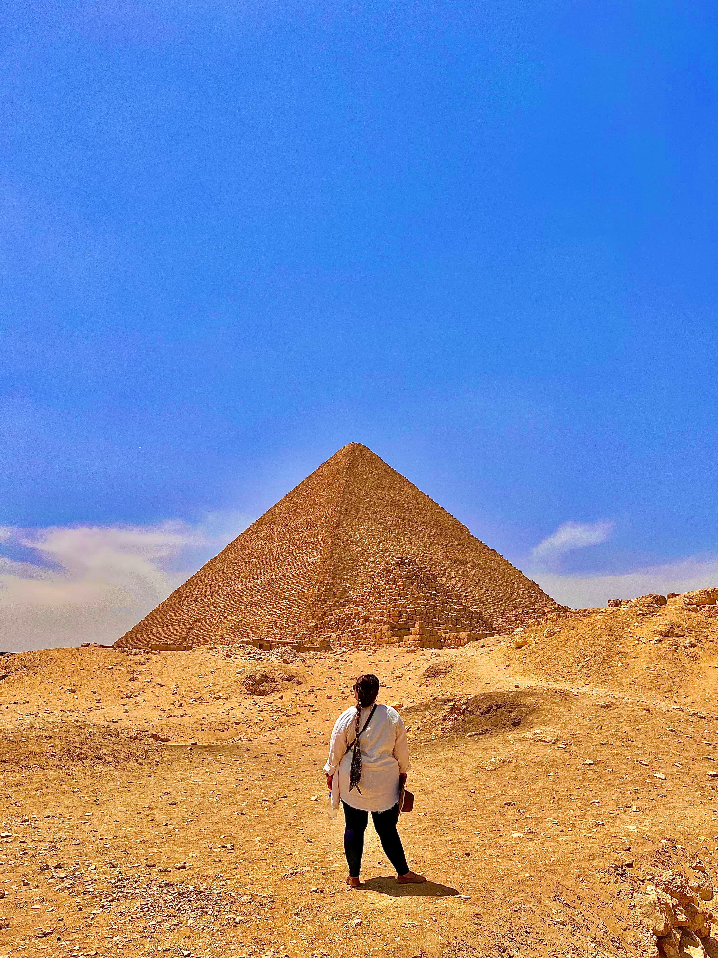 Advisor standing in front of a pyramid with a blue sky overhead.