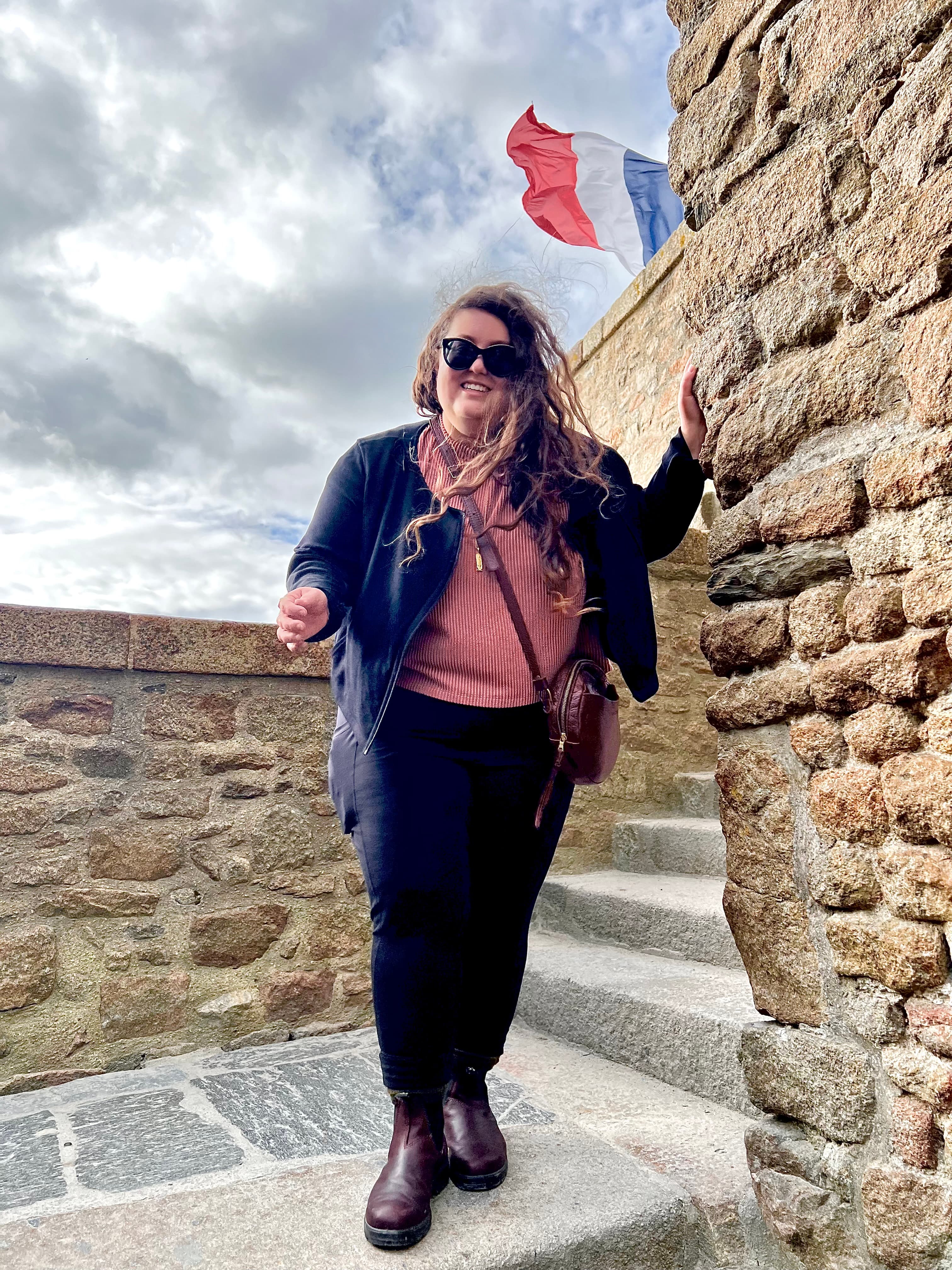 Advisor leaning on a stone building with a French flag in the background.