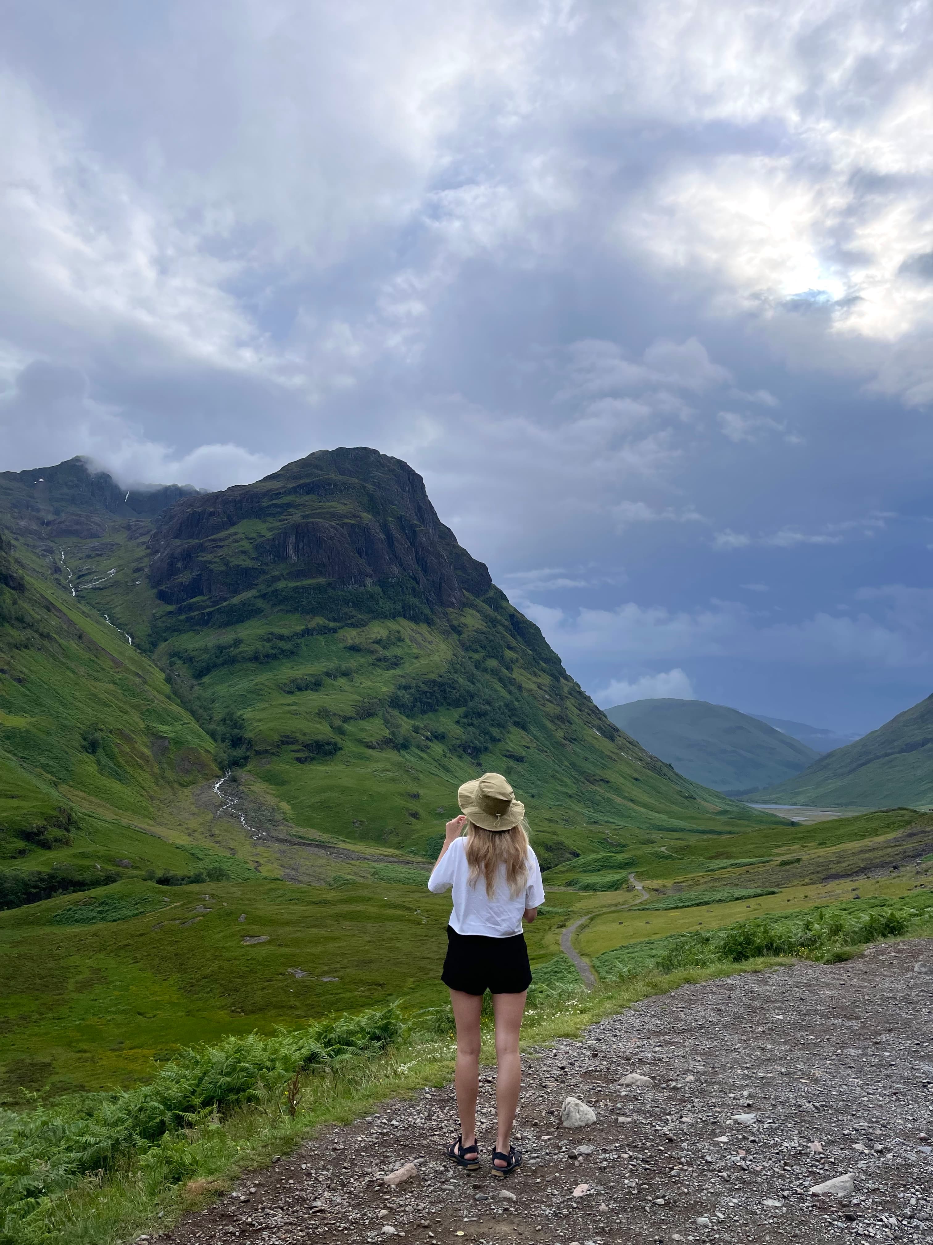 Nicola posing outdoors on a trail by the mountains.
