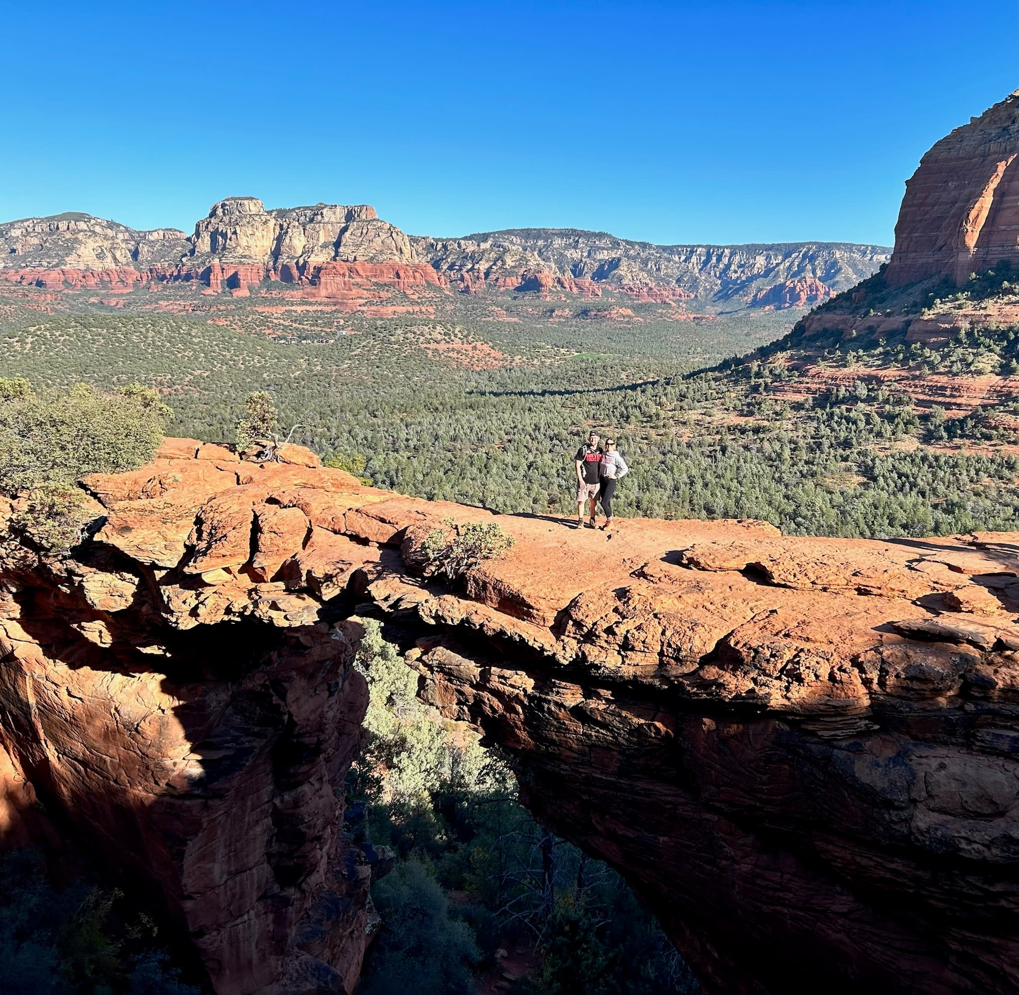 Hiker scaling a rocky shelf in a dessert lanscape on a sunny day.