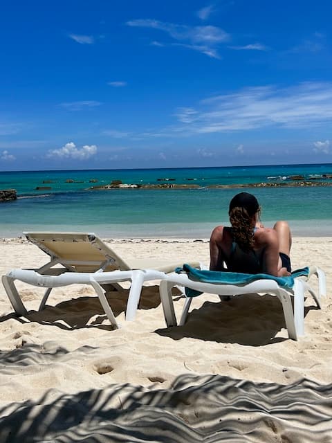 A person lounging on a beach while staring out at the ocean.