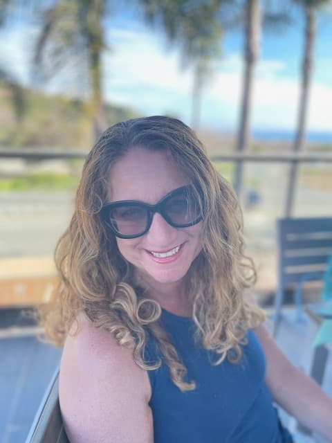 An advisor sitting outside and posing for a photo while wearing black sunglasses.