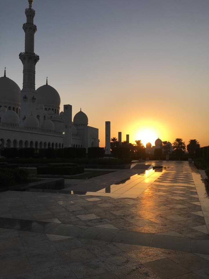 A view of a sunset with a water way and buildings in the distance.