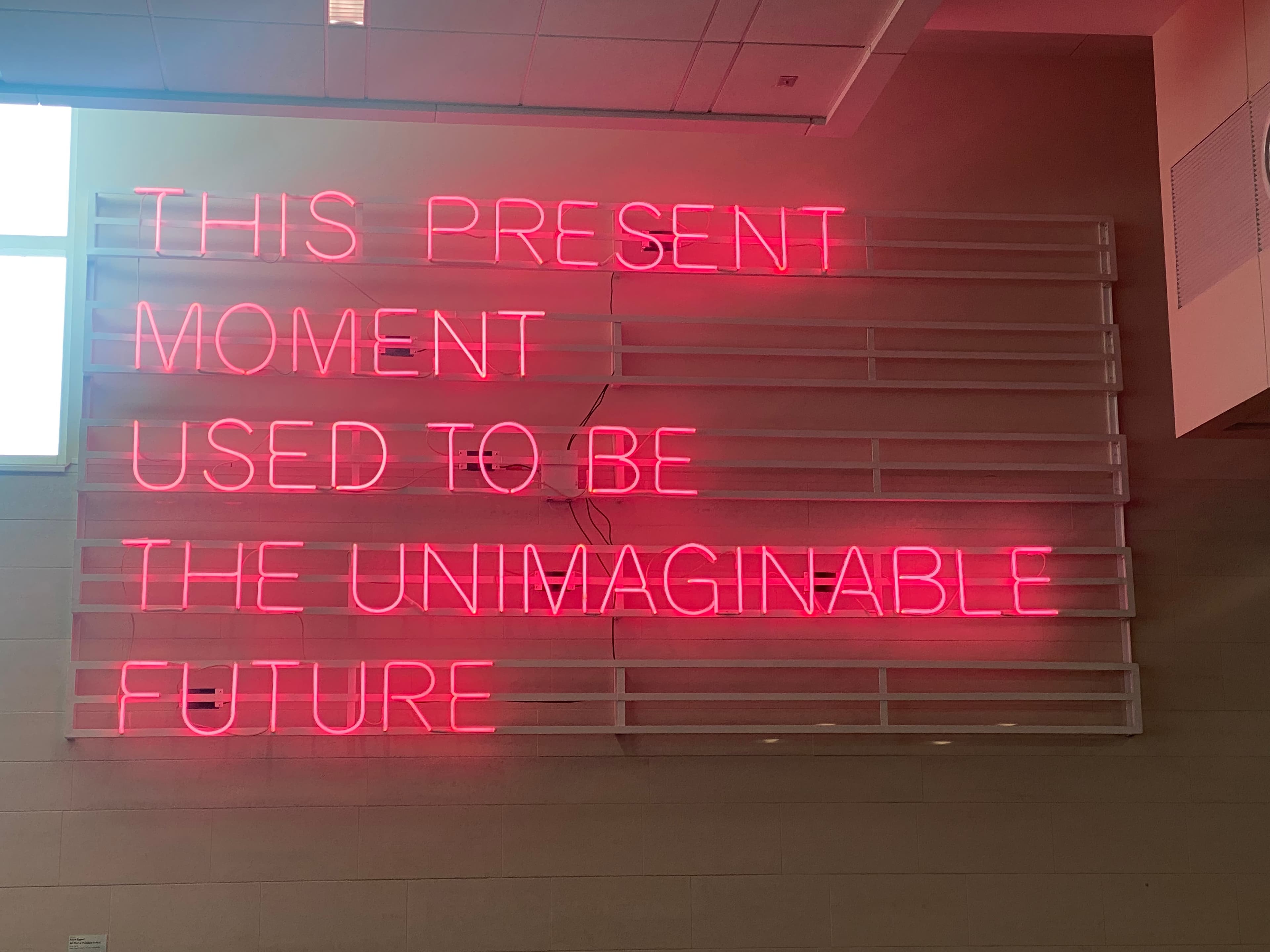 A neon say that reads: "This moment used to be the unimaginable future."