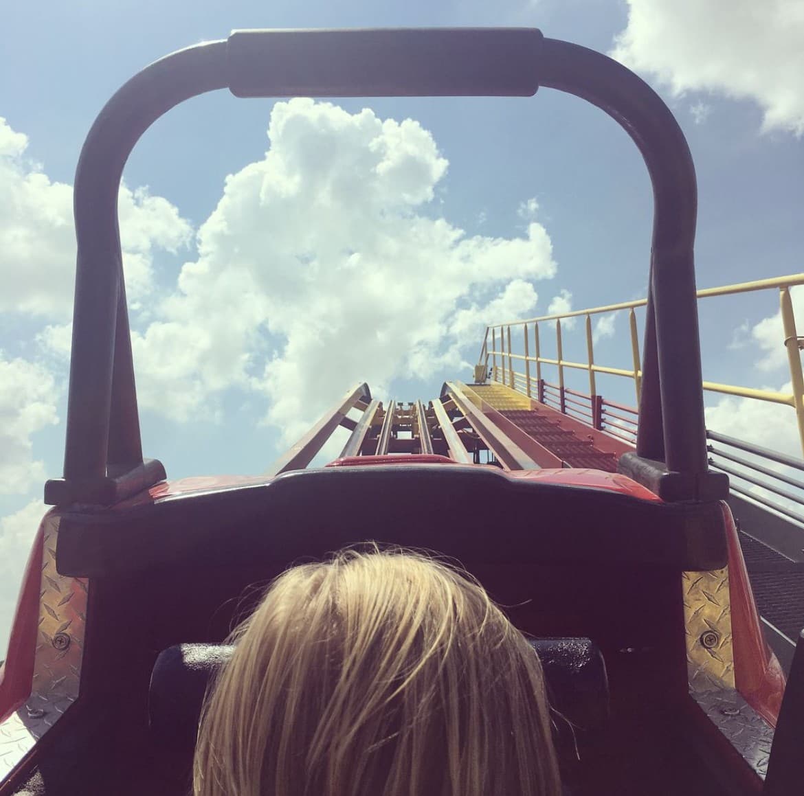 A view of people on a rollercoaster during the day.