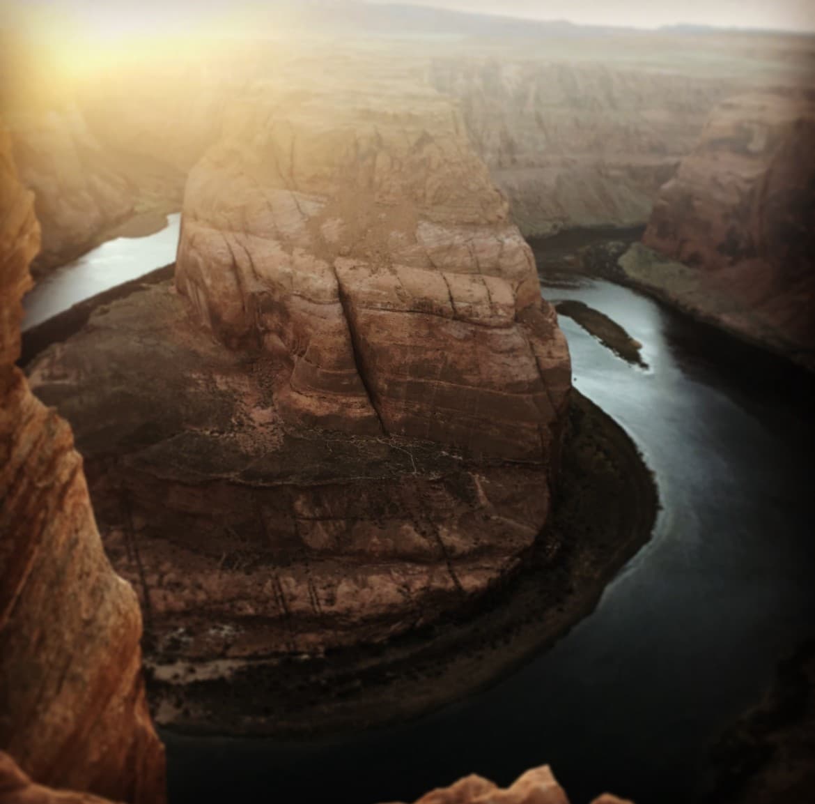 A view of a canyon with a water way and large cliffs at dusk.