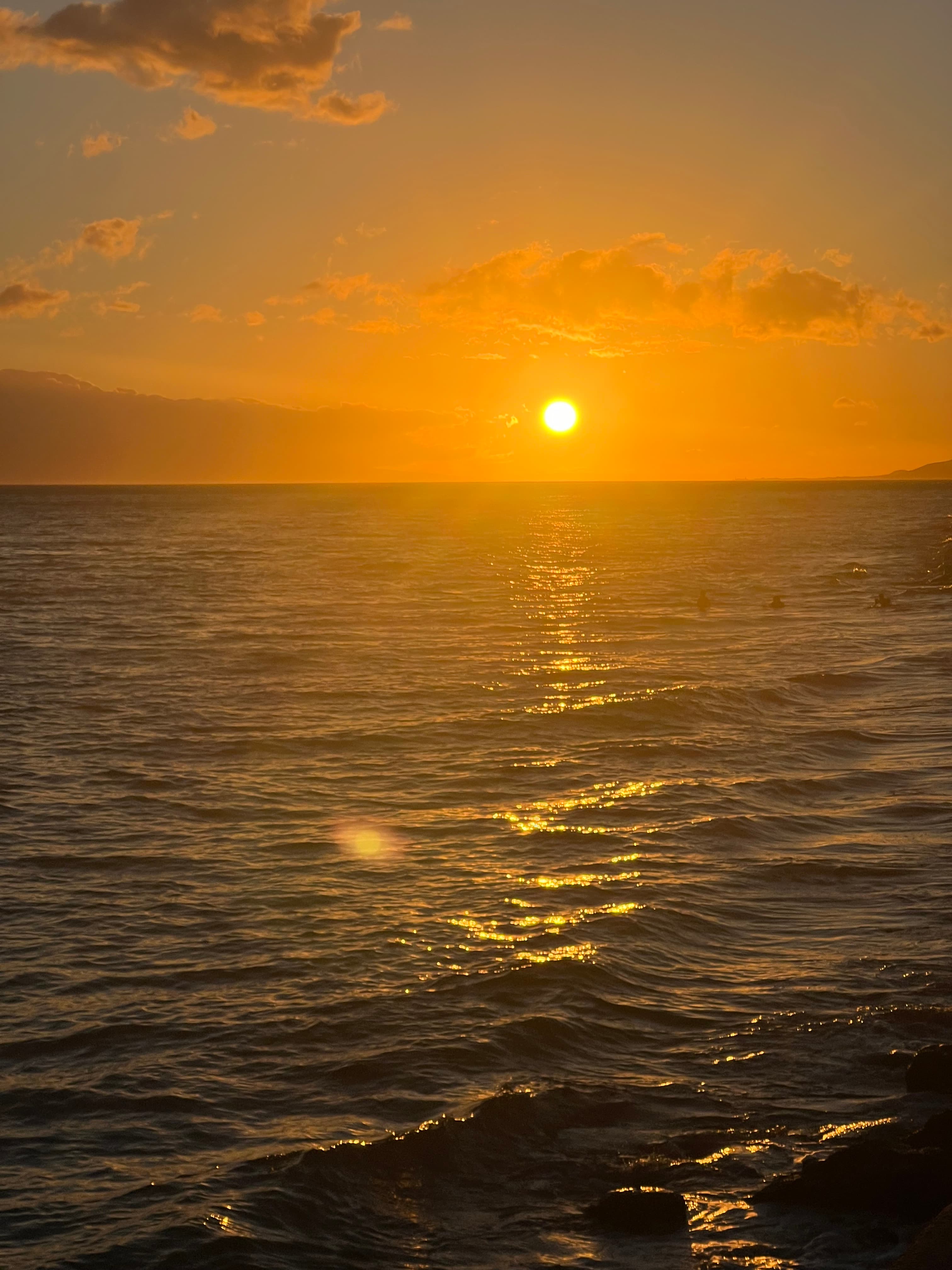 The sun sets over an ocean view as waves lap.
