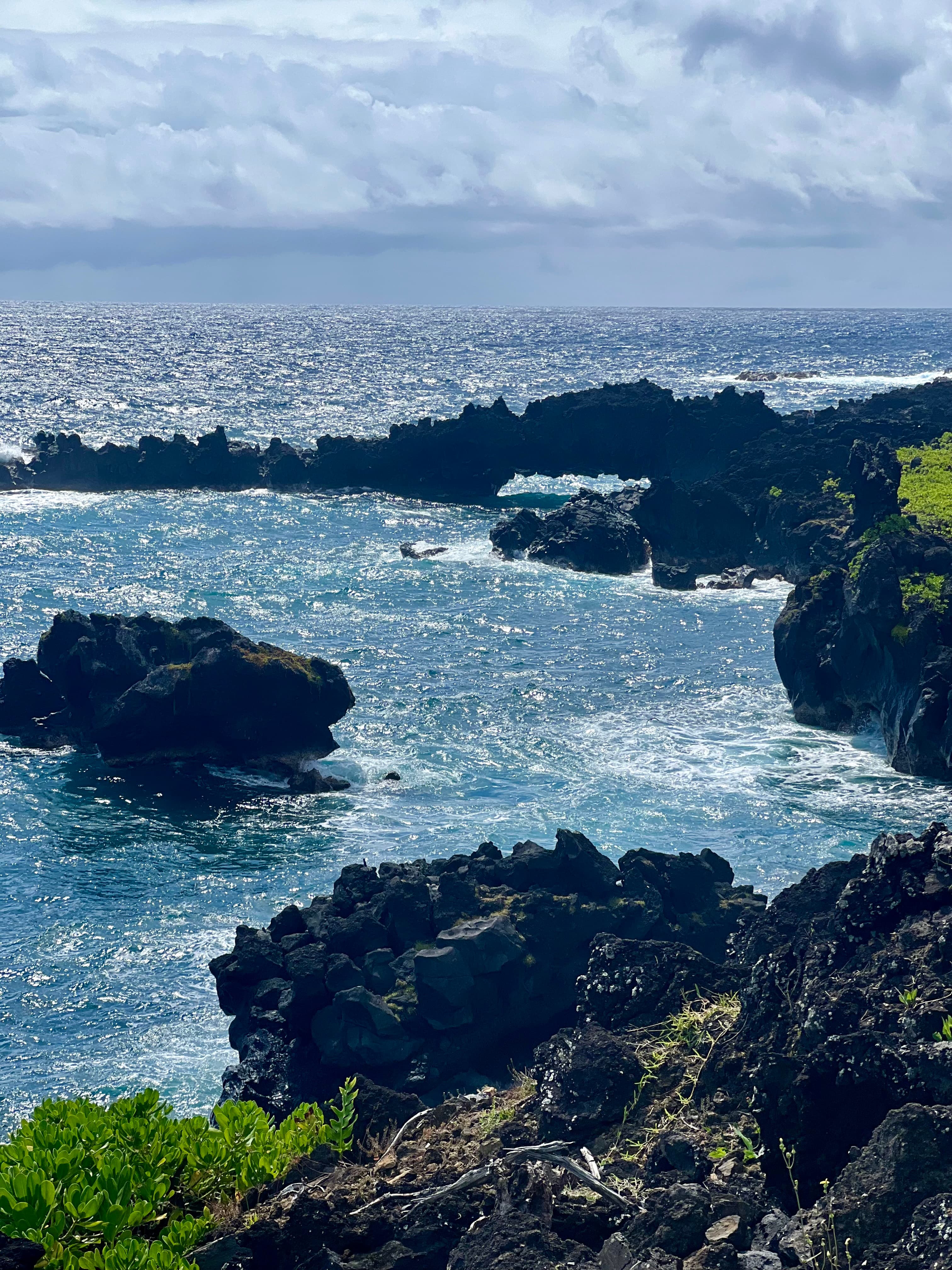 A glistening ocean view near the rocky shore on a sunny day.