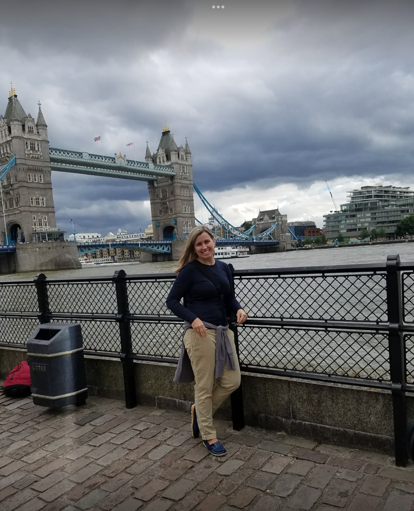 Advisor posing on a walkway in London with a bridge in the distance and a waterway.