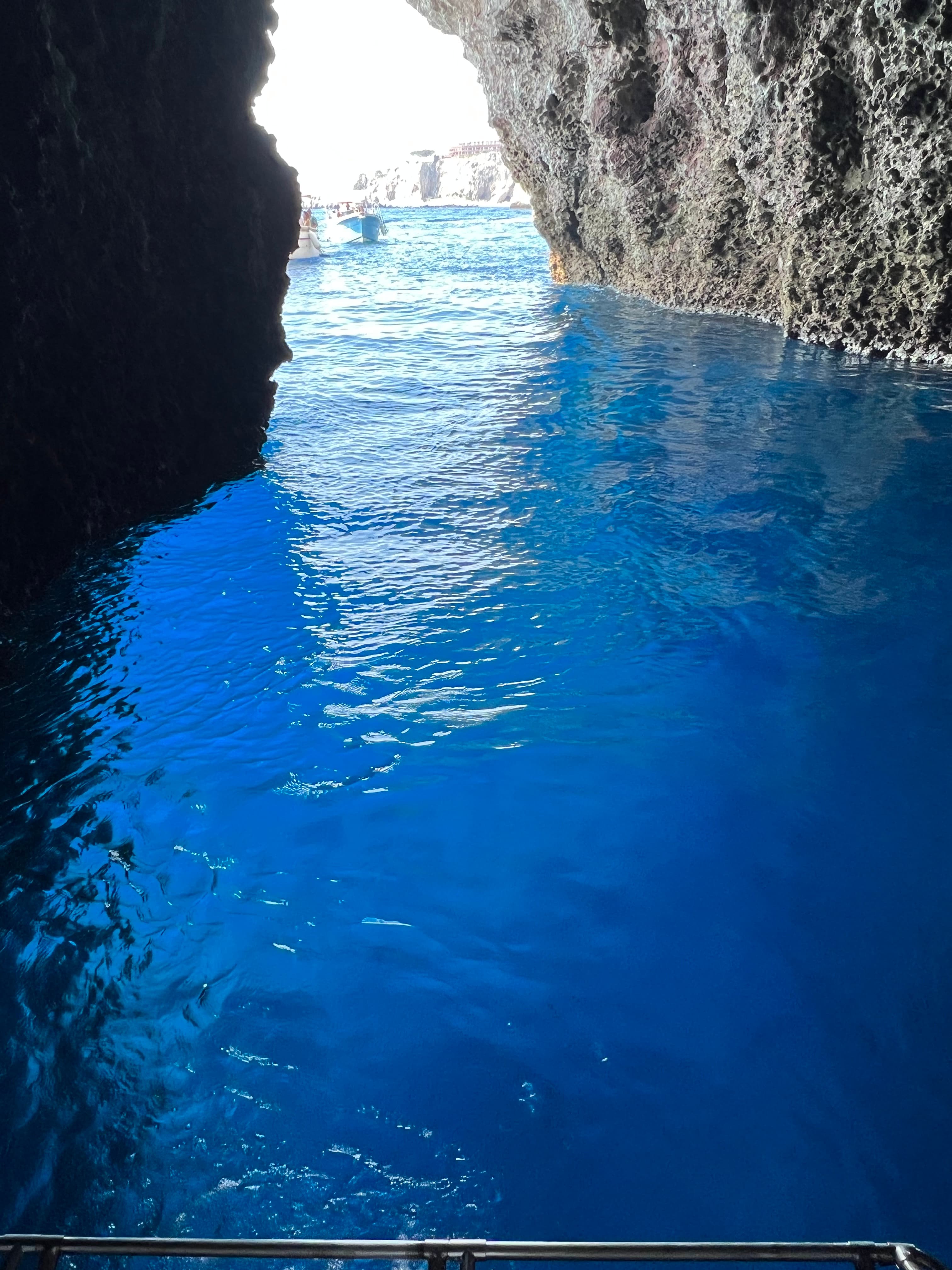 View of blue water in a cave with sunlight visible at the opening