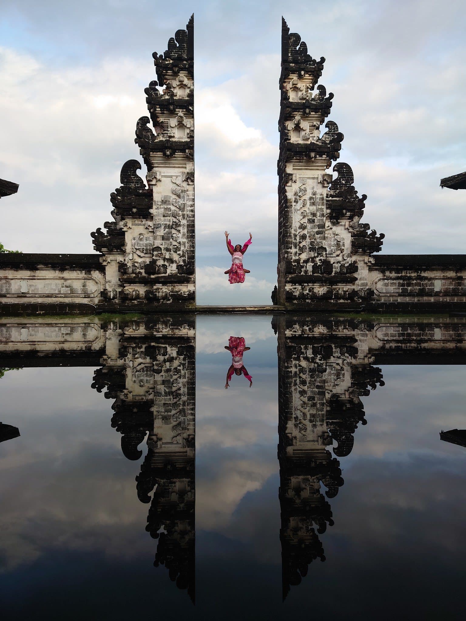 A large marble gate stands in the center of reflecting pools on a sunny day.