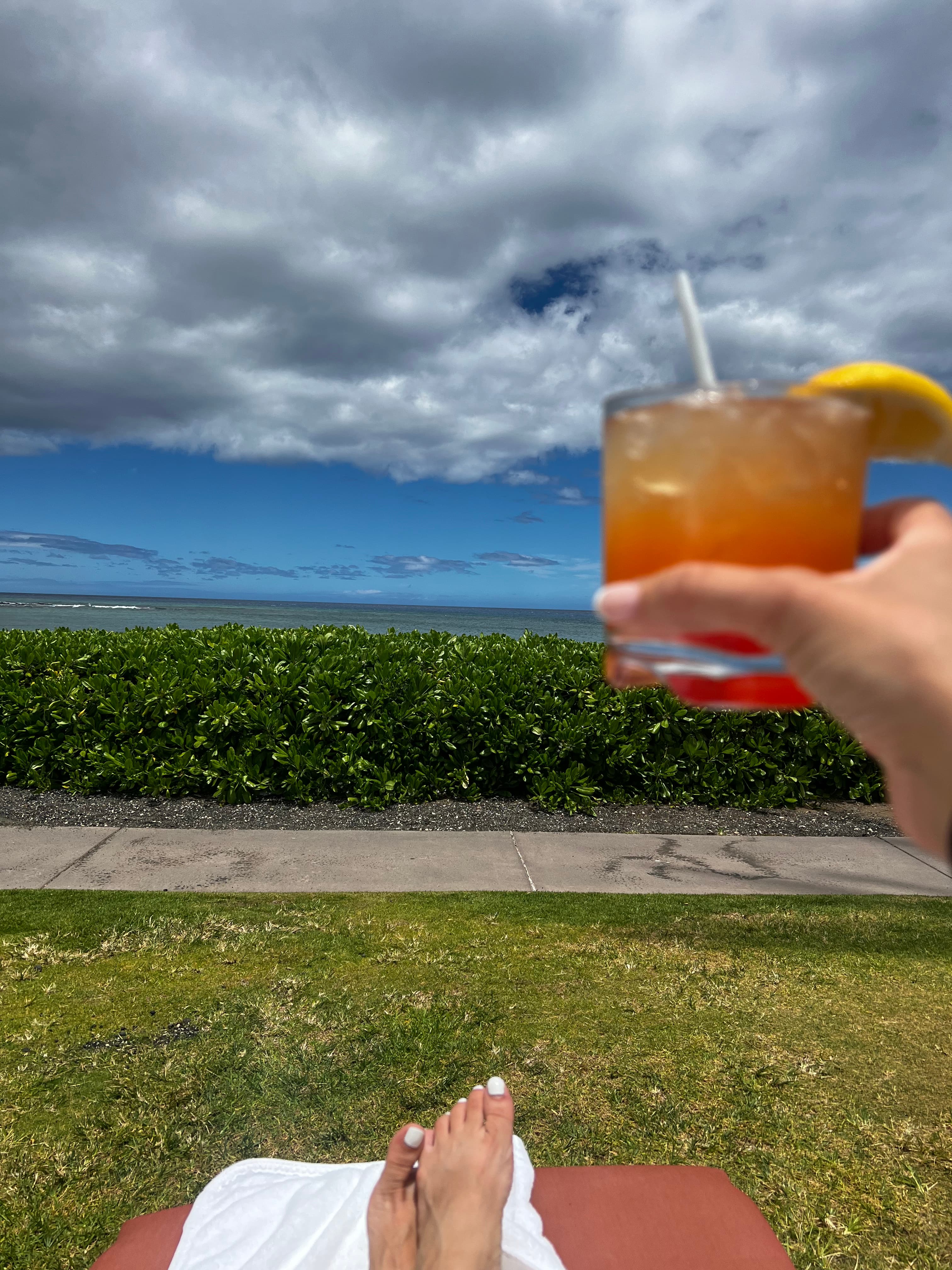 Image of advisor enjoying a cocktail with the ocean in the distance.