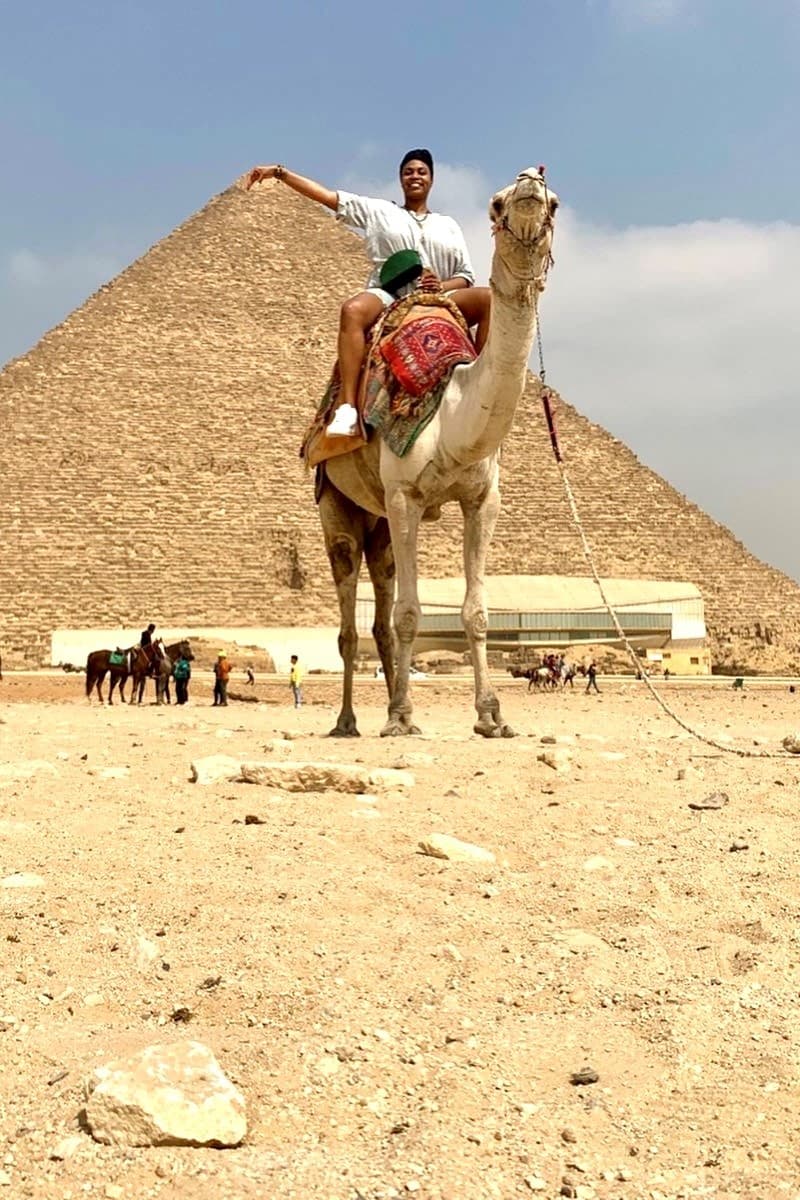 Advisor on a camel’s back in front of the pyramid of Giza during the daytime