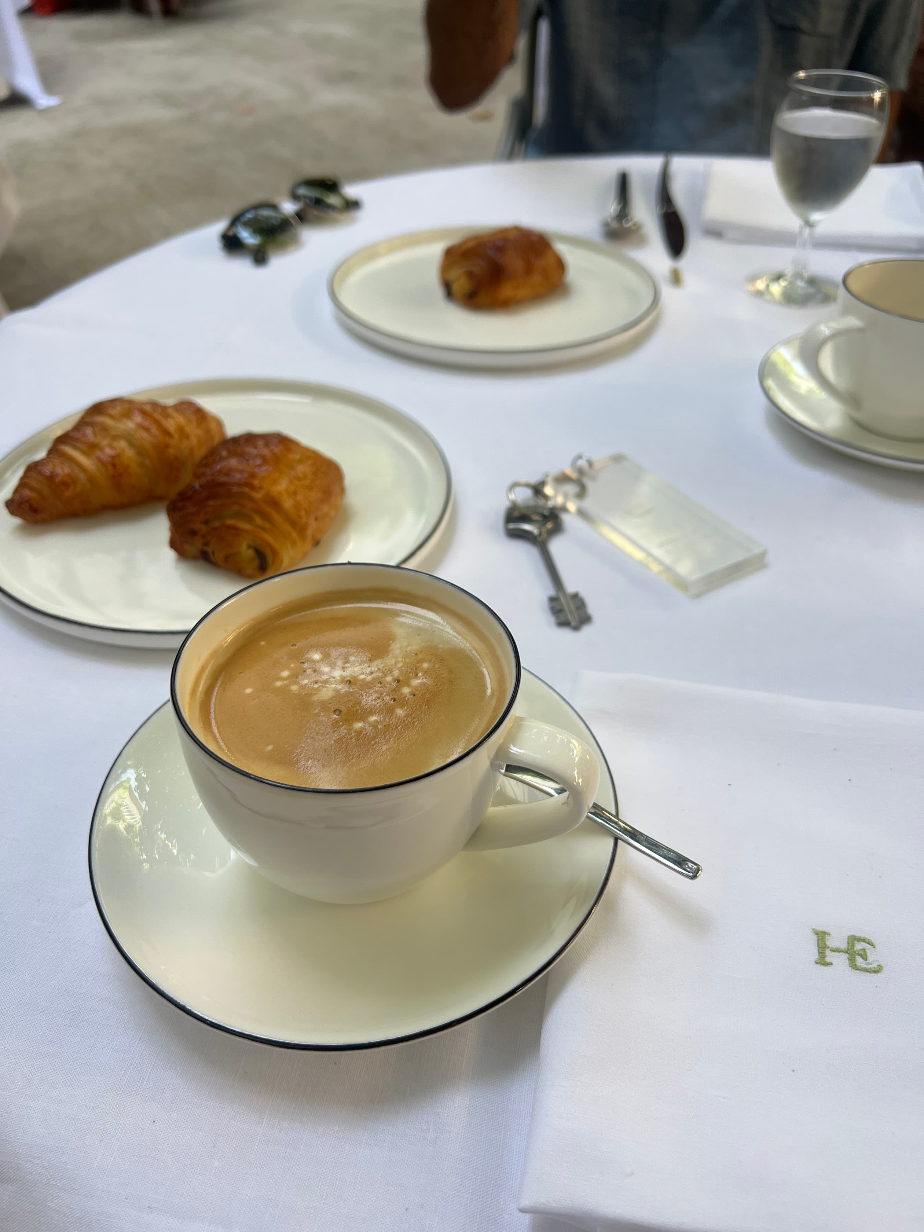 An image of pastries and coffee on a table with a white table cloth.