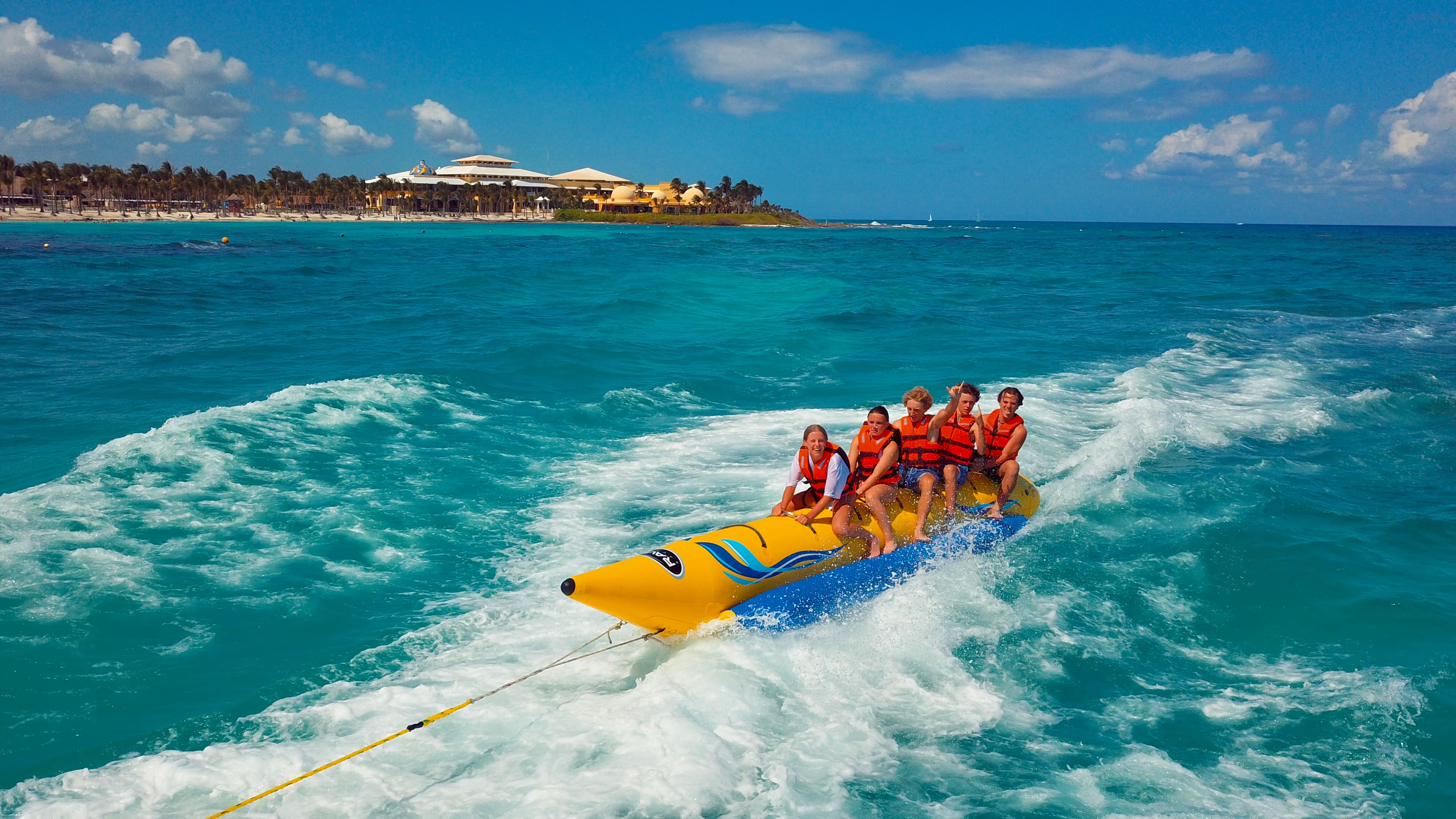 A group of individuals enjoying a thrilling ride on a banana boat, laughing and splashing in the water.