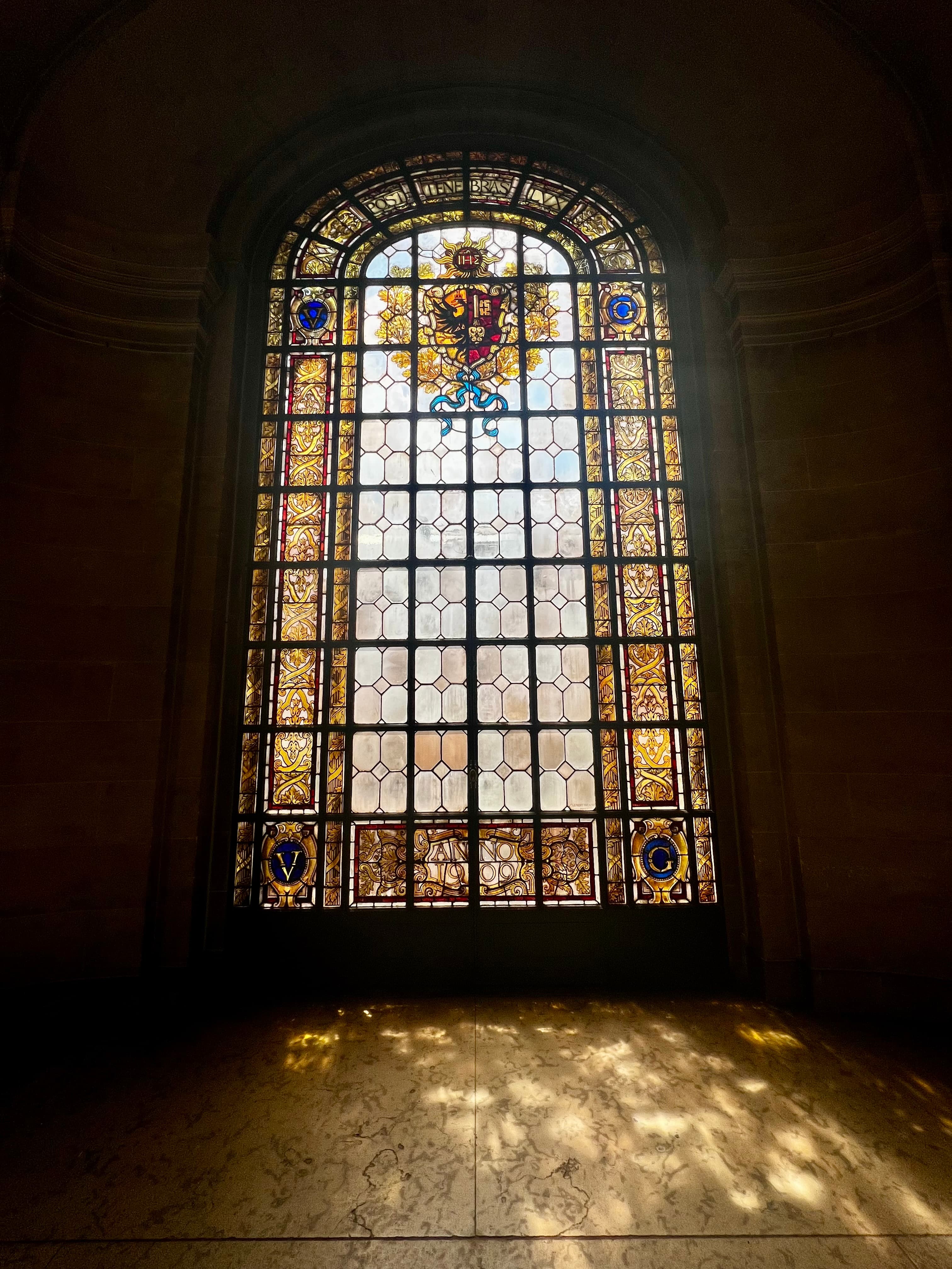 Pretty view of sunlight coming through a large stained glass window and reflecting on the floor