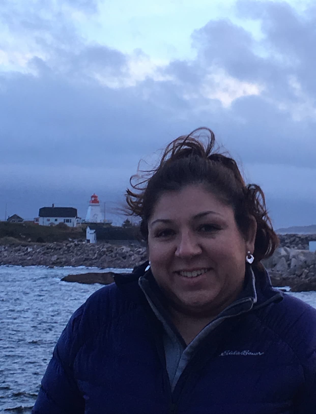 A woman stands gracefully by the water's edge at the beach during the early evening.
