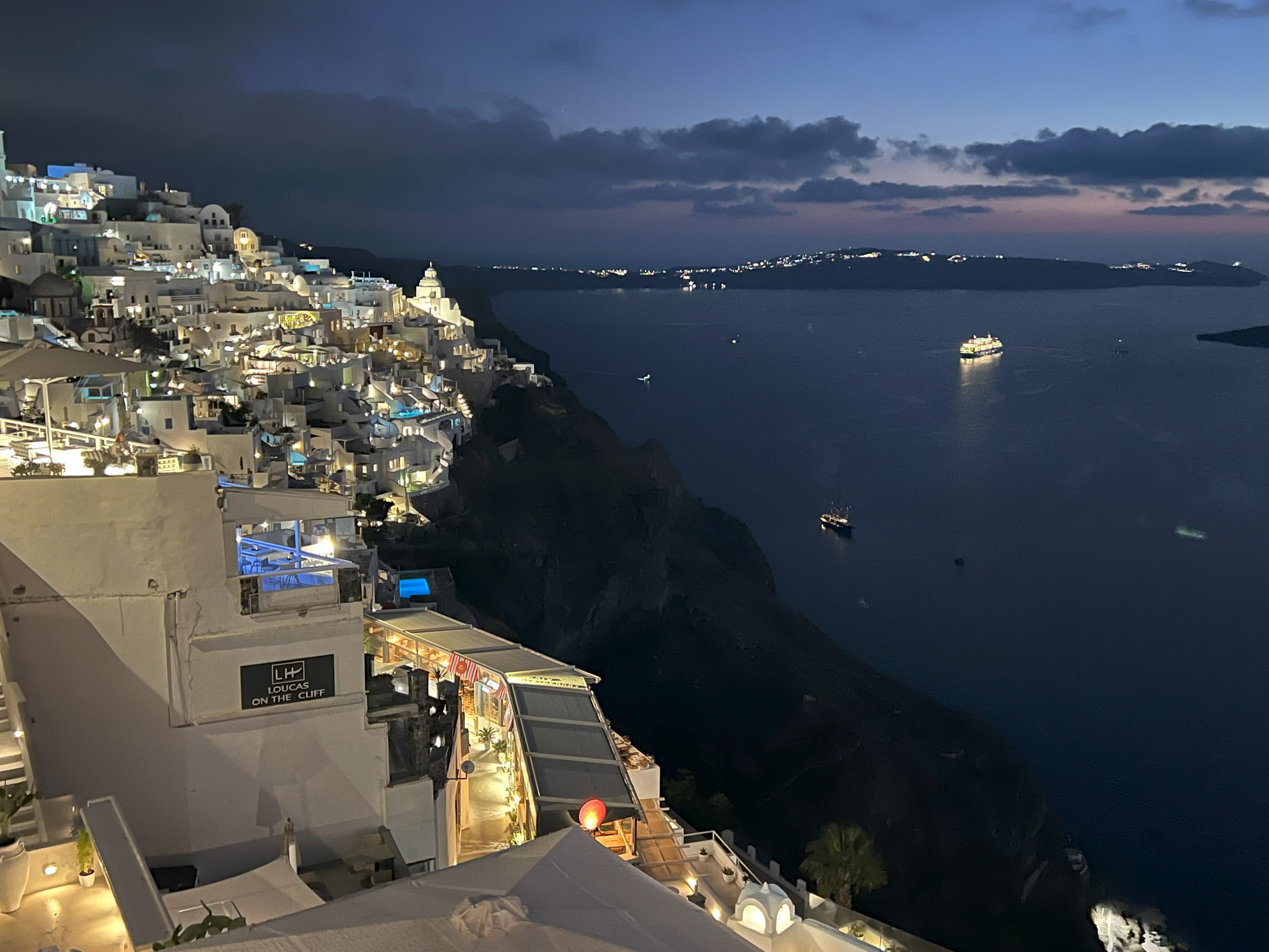 A panoramic view from the hilltop at night, showcasing a starry sky and distant city lights twinkling below.