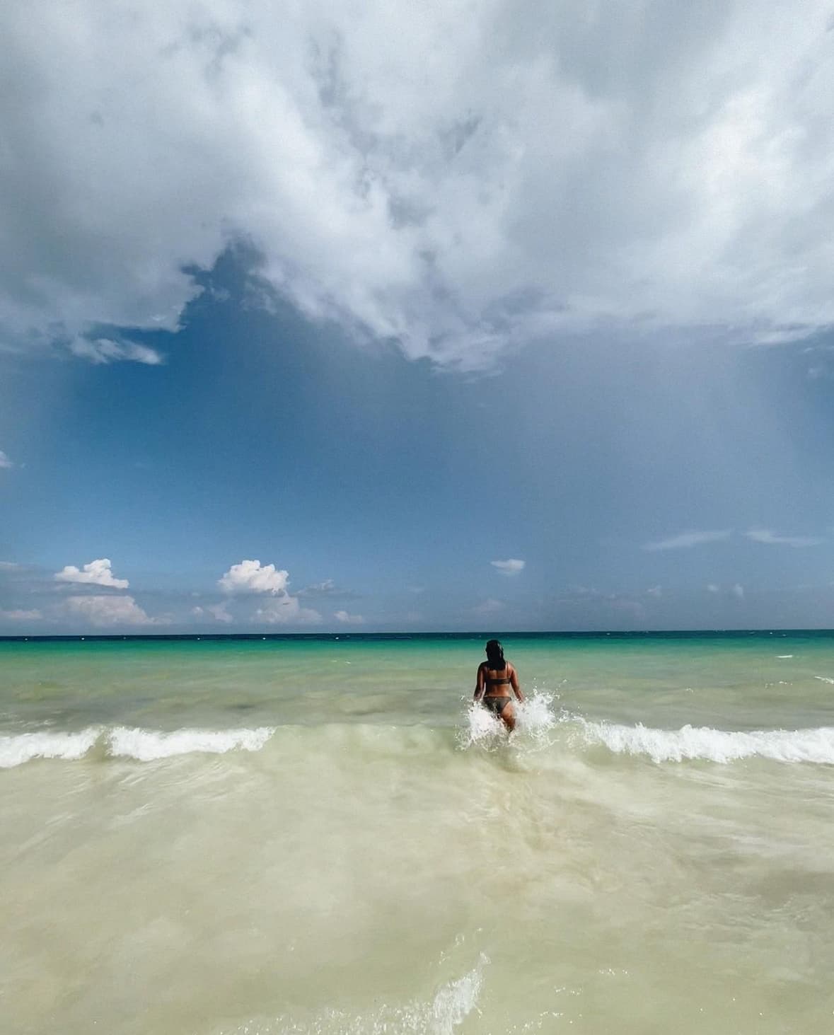 Kalei stands in the ocean, surrounded by waves, enjoying the water.