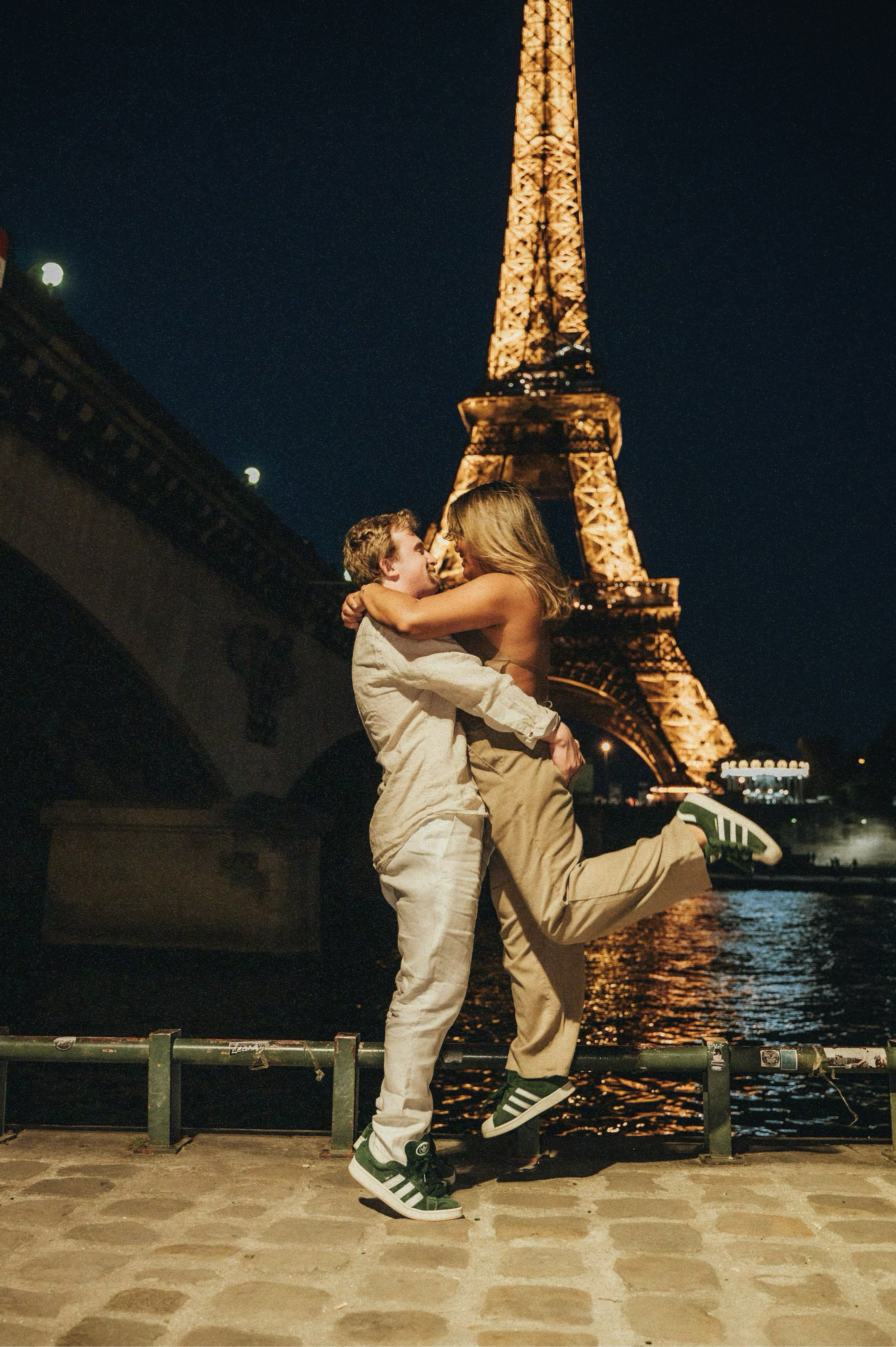 A couple shares a warm embrace in front of the iconic Eiffel Tower.